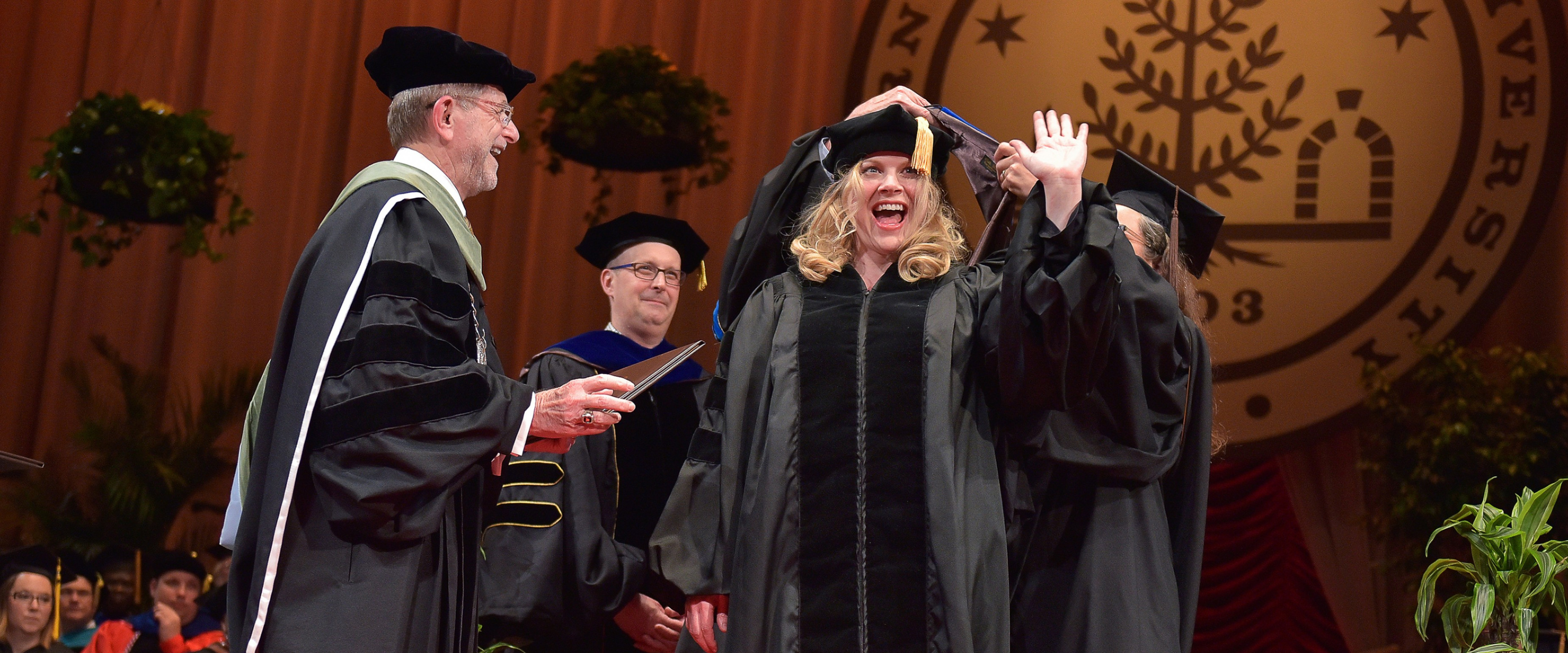 Aimee Valentine waves as she receives a Doctor of Philosophy in English