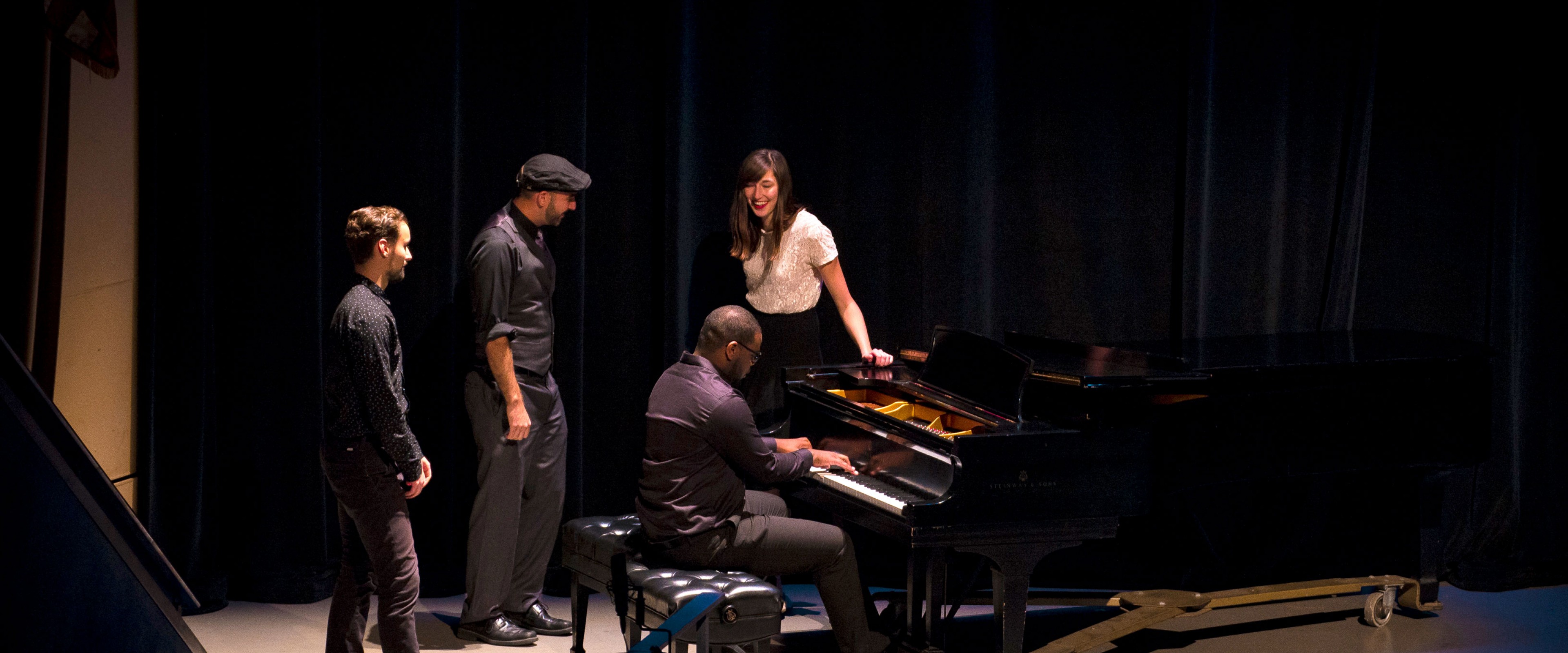 Group of four jazz students performing on stage, singing and playing piano.