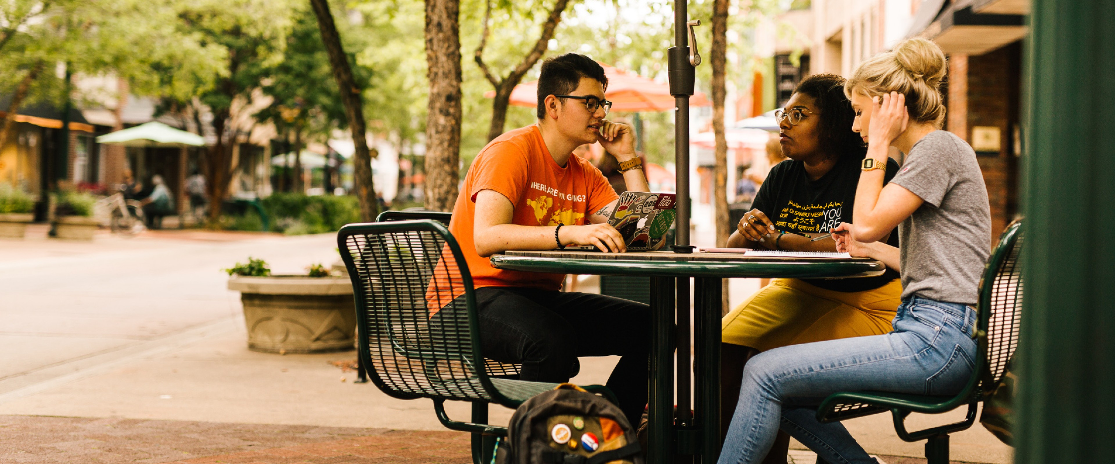 3 students sitting at an outdoor table in downtown Kalamazoo