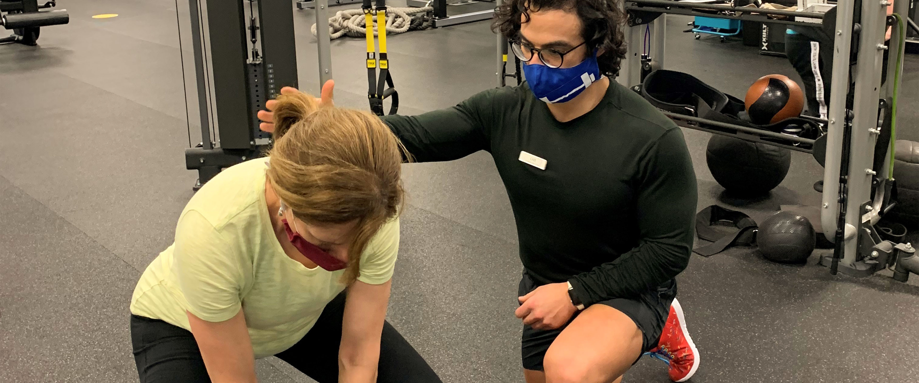 Personal trainer assisting a middle aged women with workout