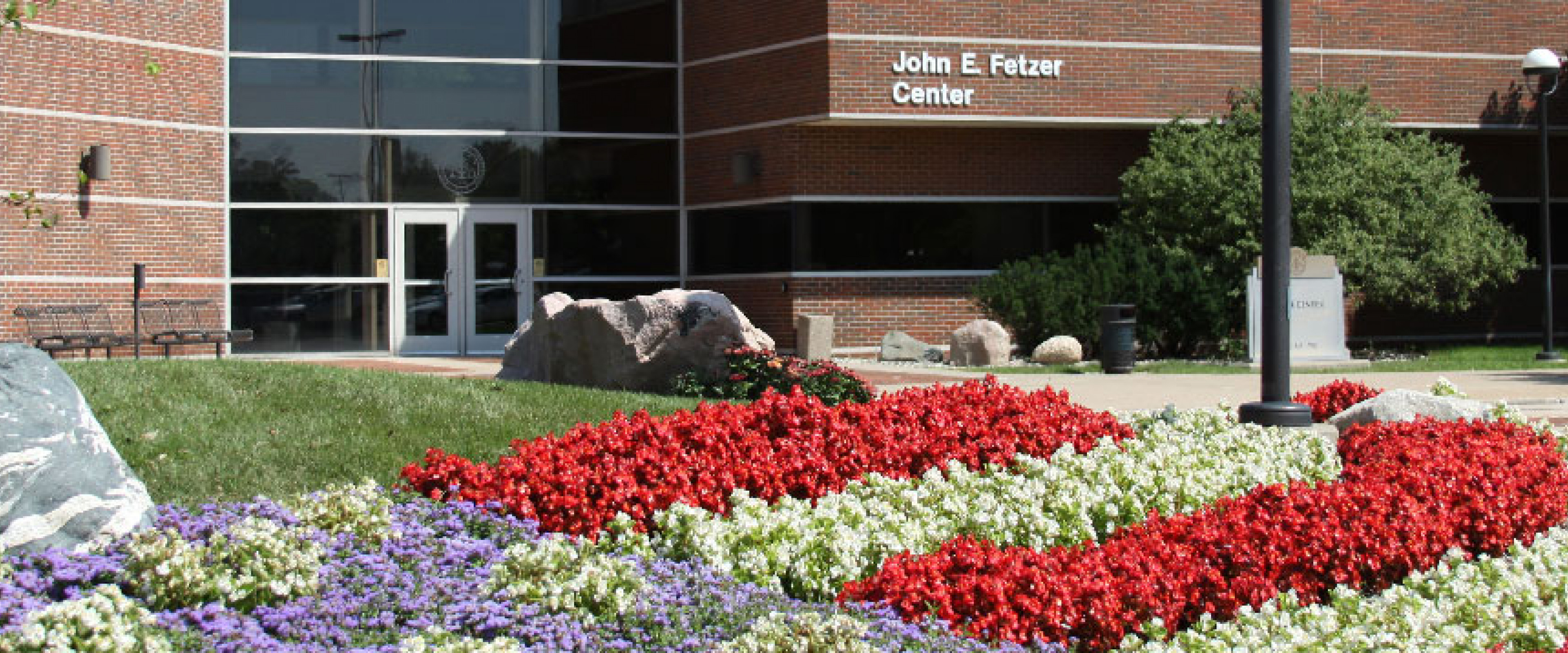 Fetzer building with purple, red and white flowers in front.