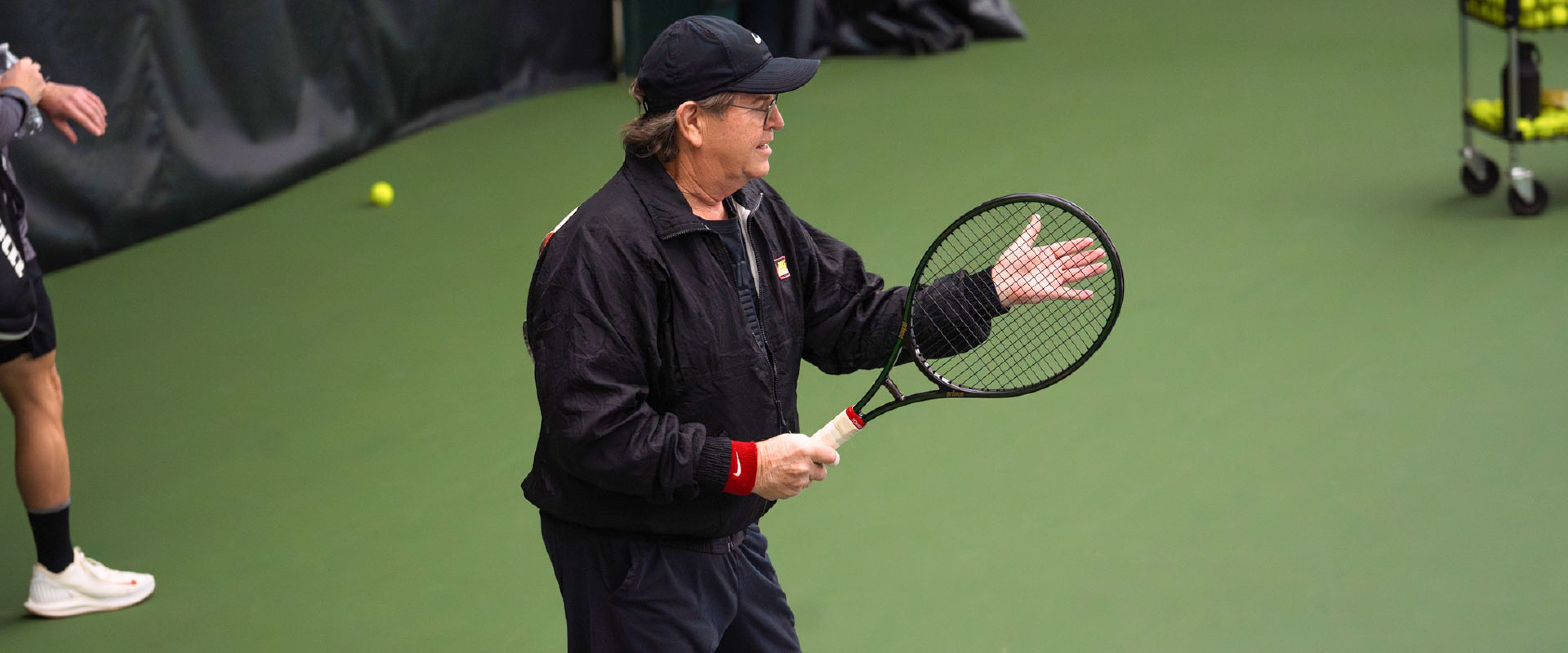 guy holding a black tennis racket wearing a black baseball hat