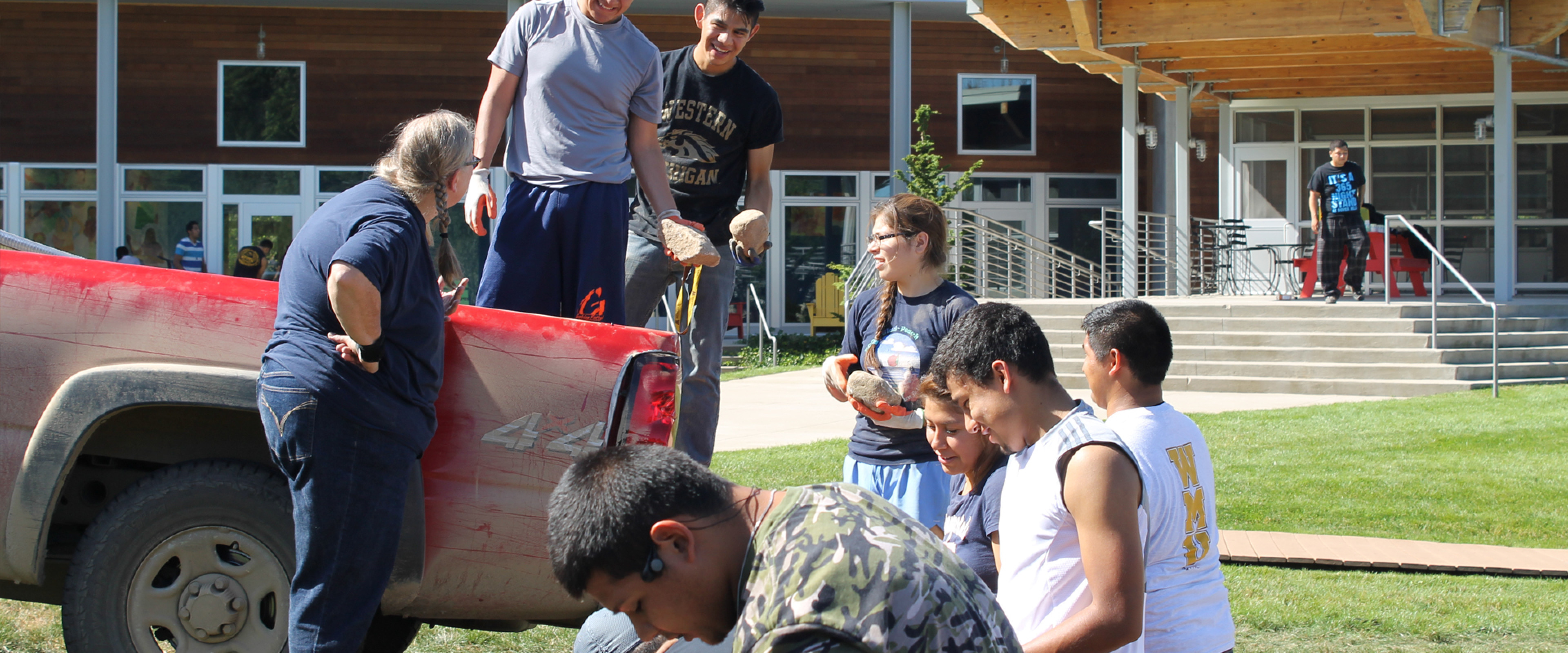 A group of students moving rocks behind a car.