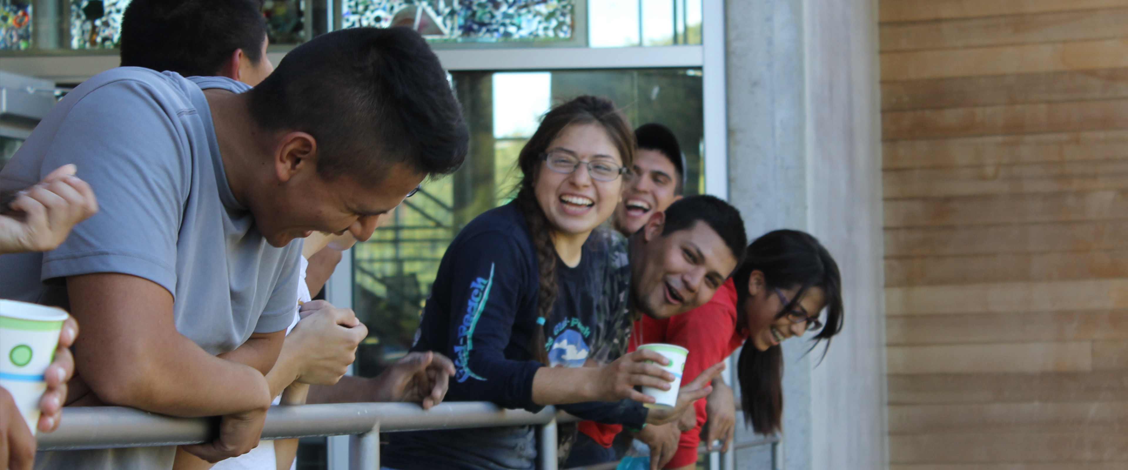 A group of students laughing over a ledge.