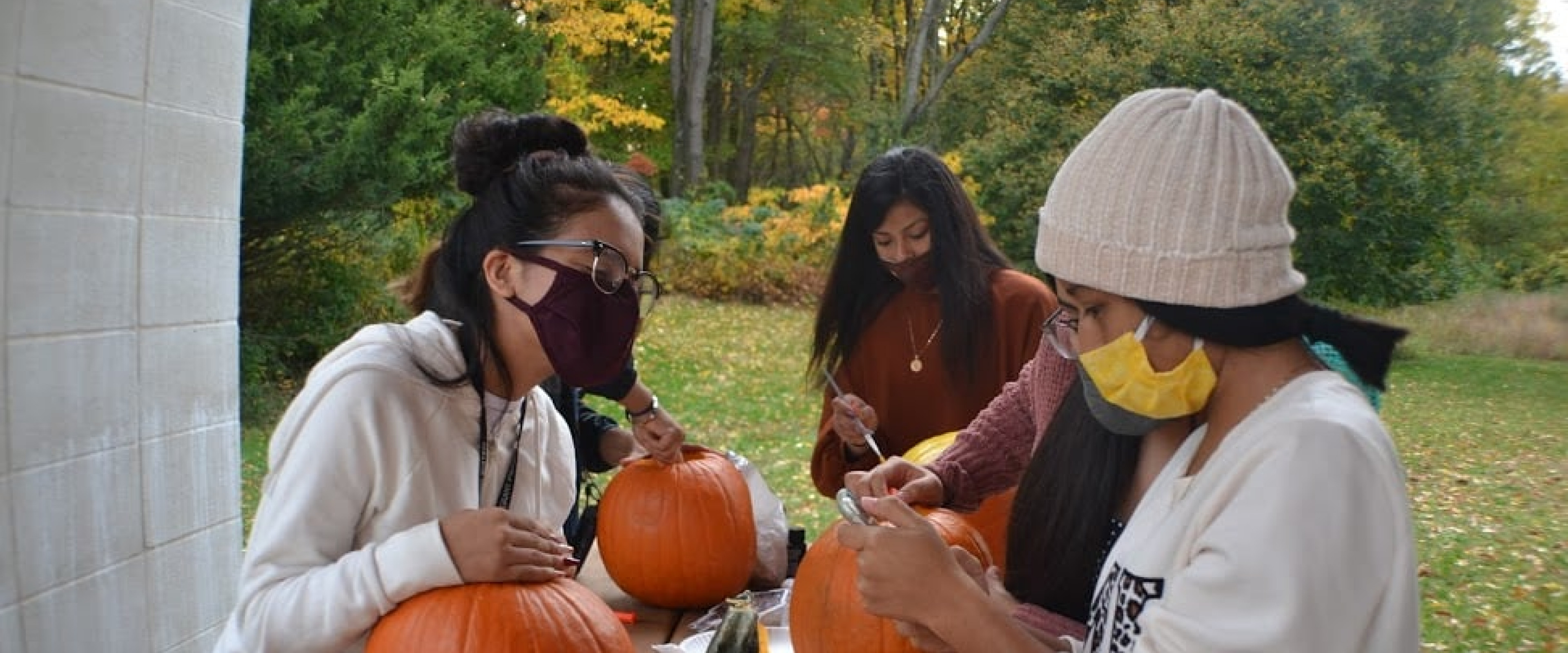 A group of students carving and painting pumpkins. 