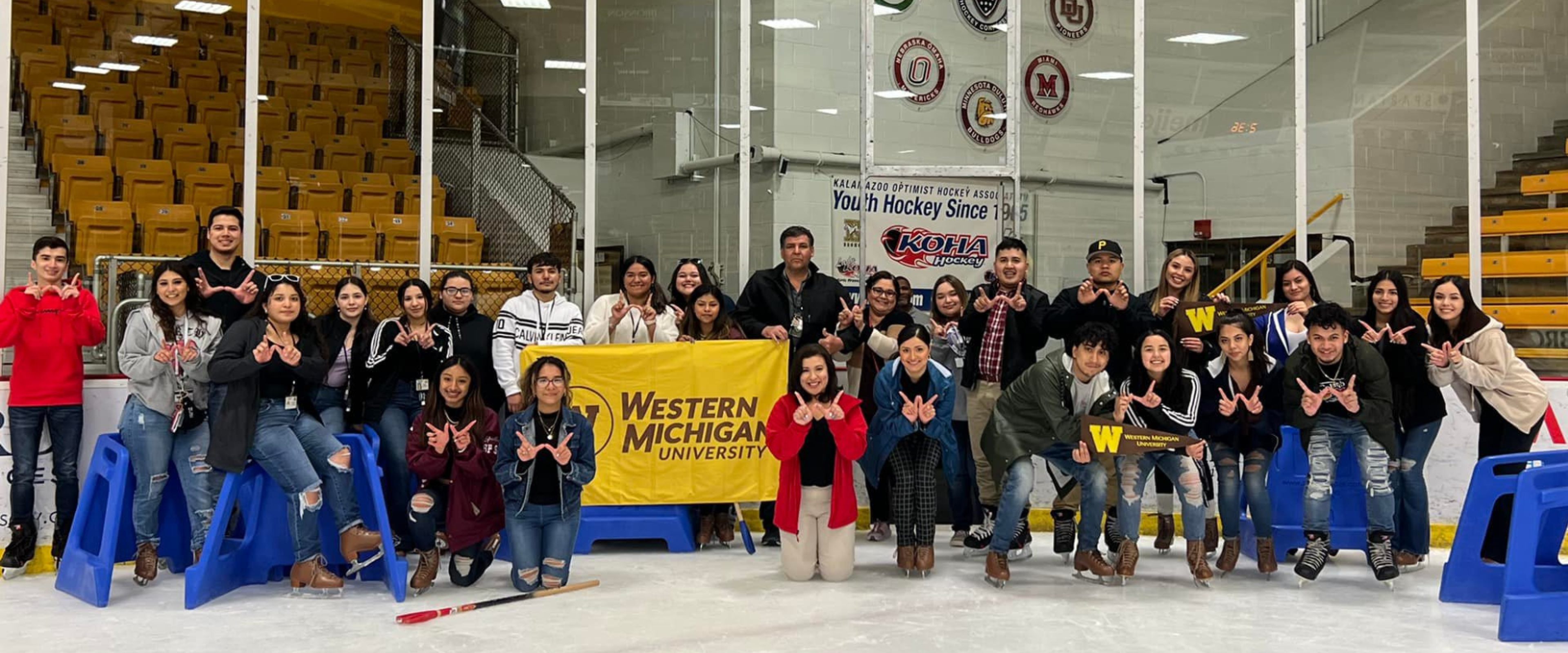 CAMP staff, scholars, and future scholars posing for a group photo in a ice hockey rink.