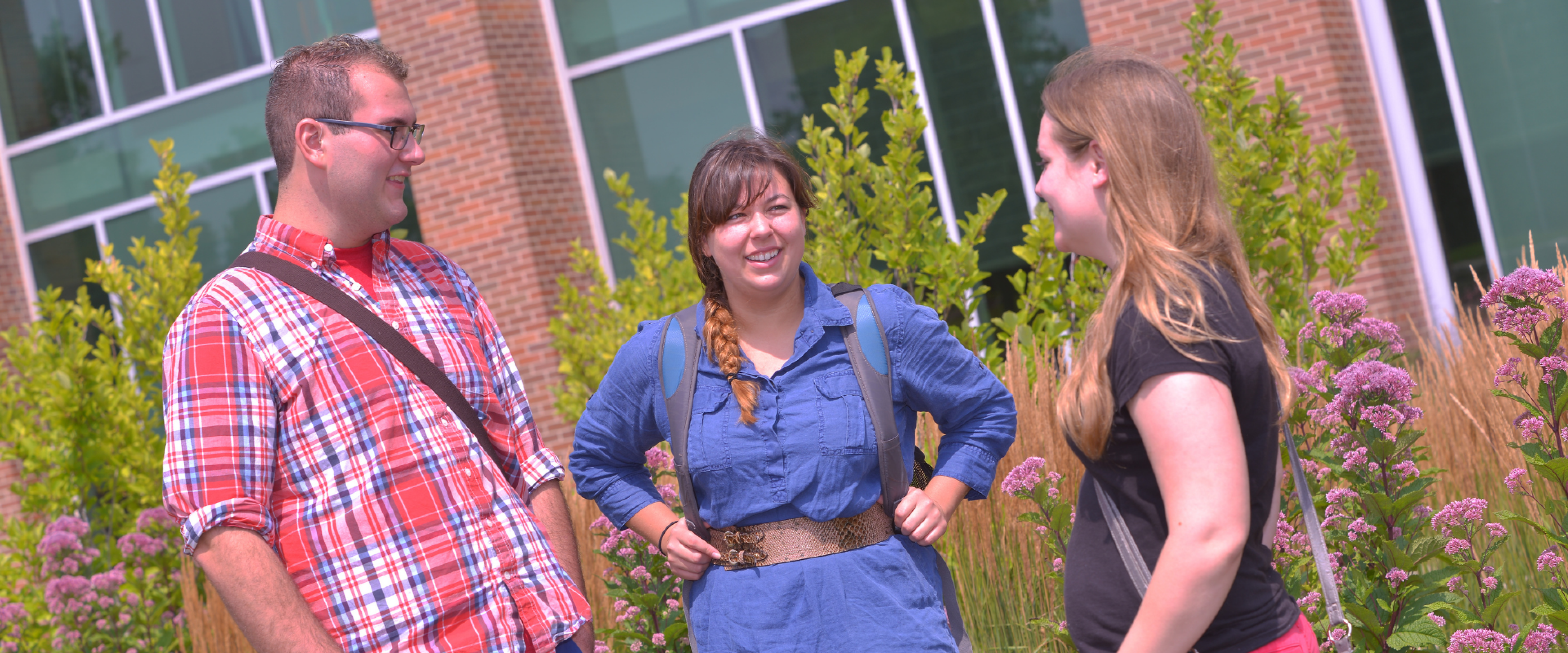 Three participants standing outside a building on campus and having a conversation.