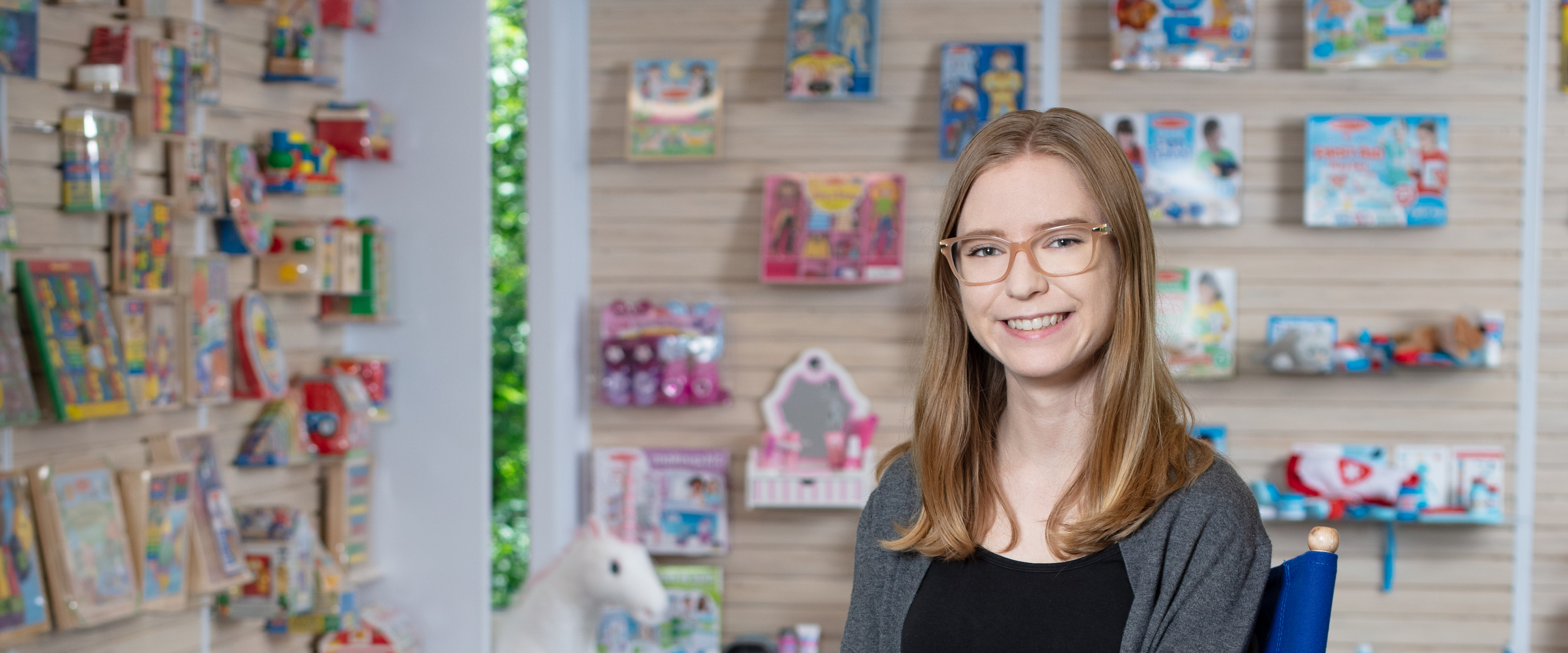 A portrait of Isabella Waite in front of a wall of toys.