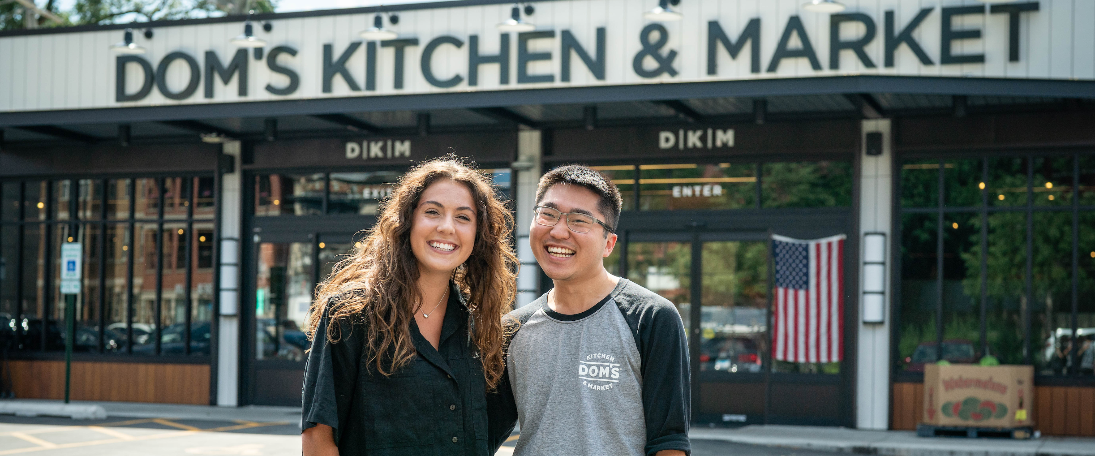 Korina Luco and Dominic Gee pose for a picture in front of Dom's Kitchen and Market.