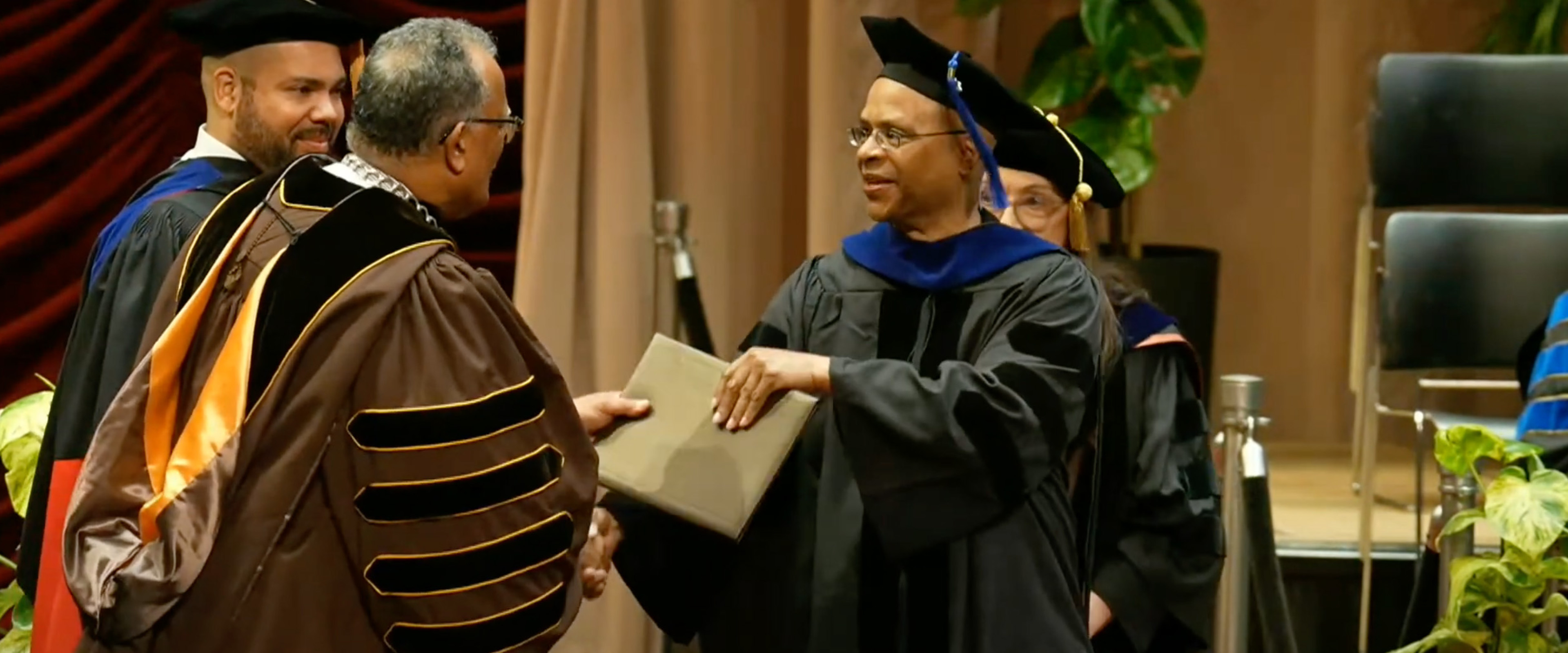 James Rhodes accepts his diploma from President Edward Montgomery as Provost Julian Vasquez Heilig looks on.