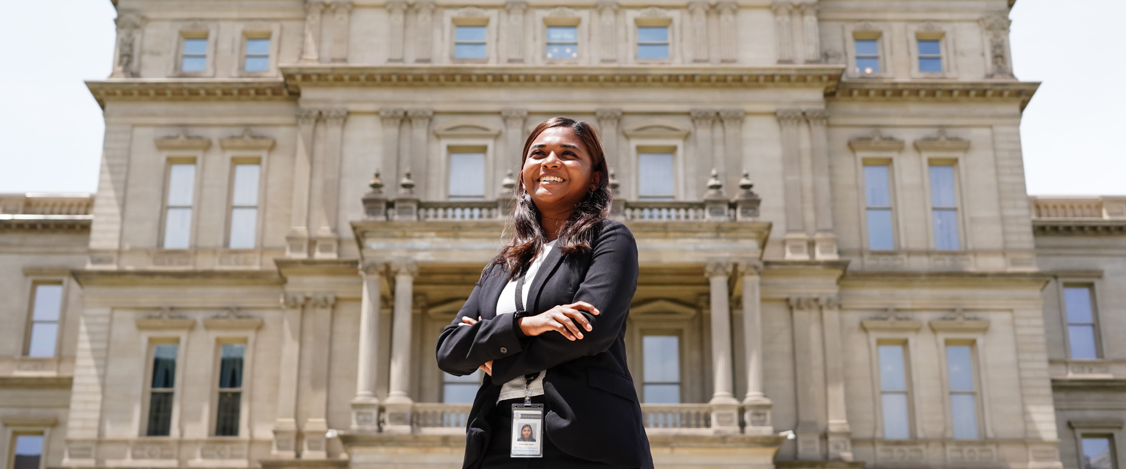 A student stands in front of the Michigan Capitol.