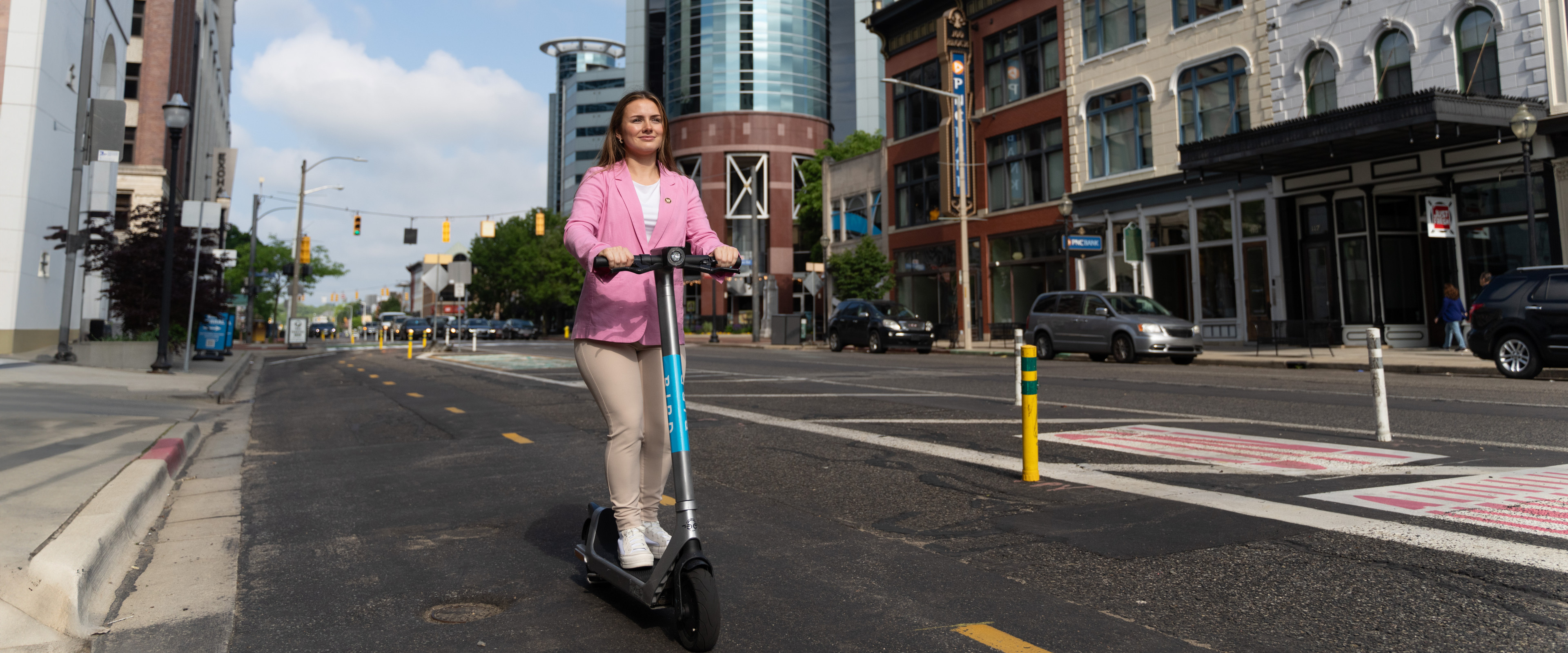 A young woman rides an electric scooter through town