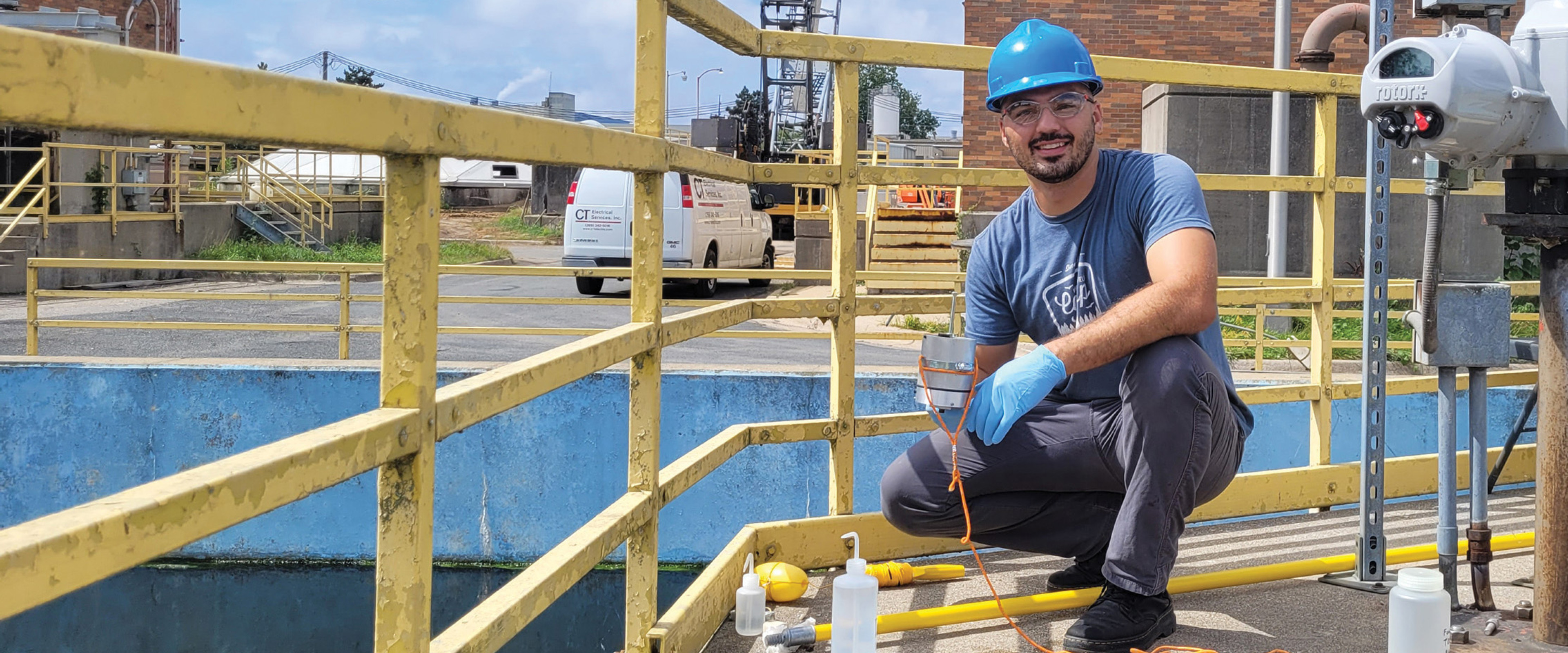 A person wearing a hard hat stands next to a water pipe