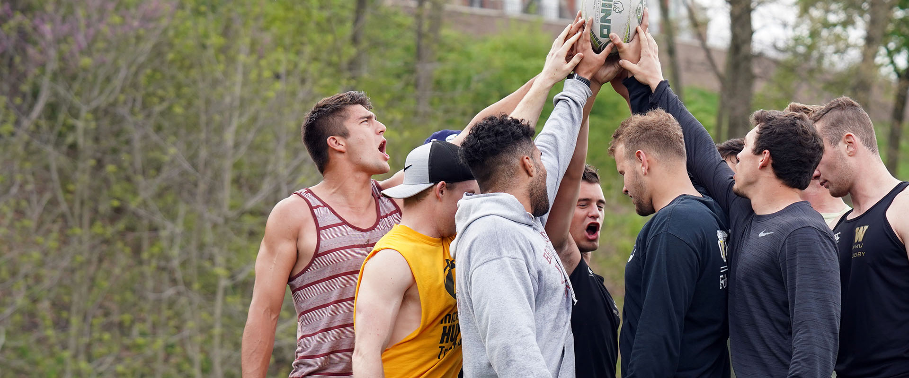 A group of WMU students doing a team cheer before a rugby match