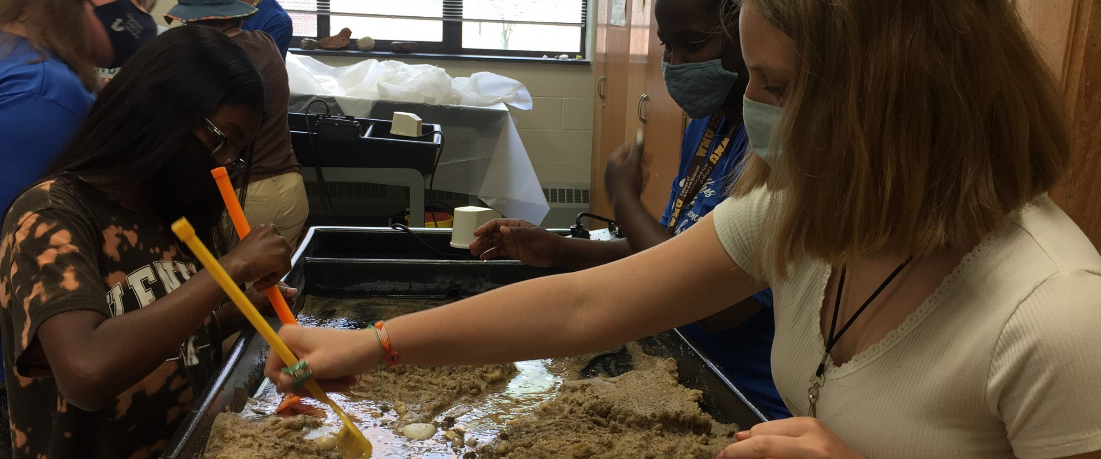 Students investigating how water moves through sand on a water/sand table