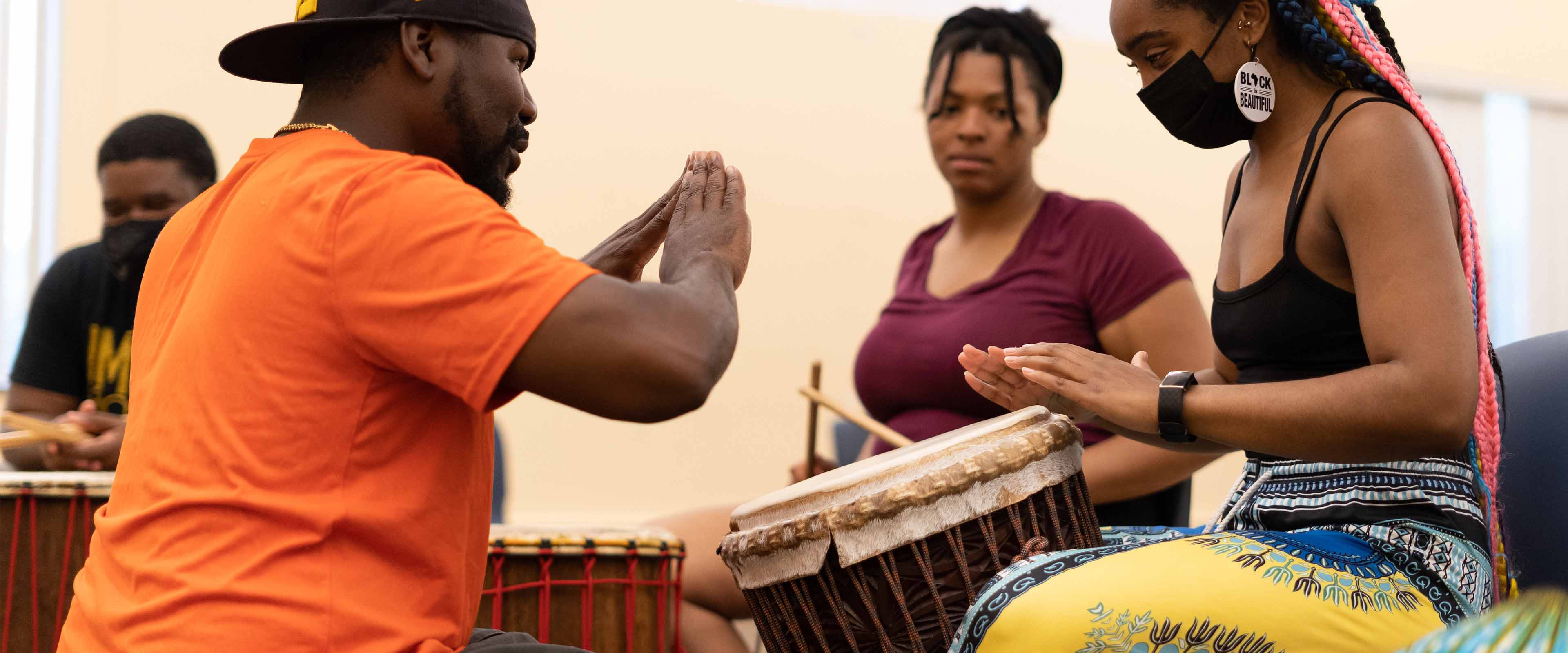 An instructor teaching a grad student how to drum.
