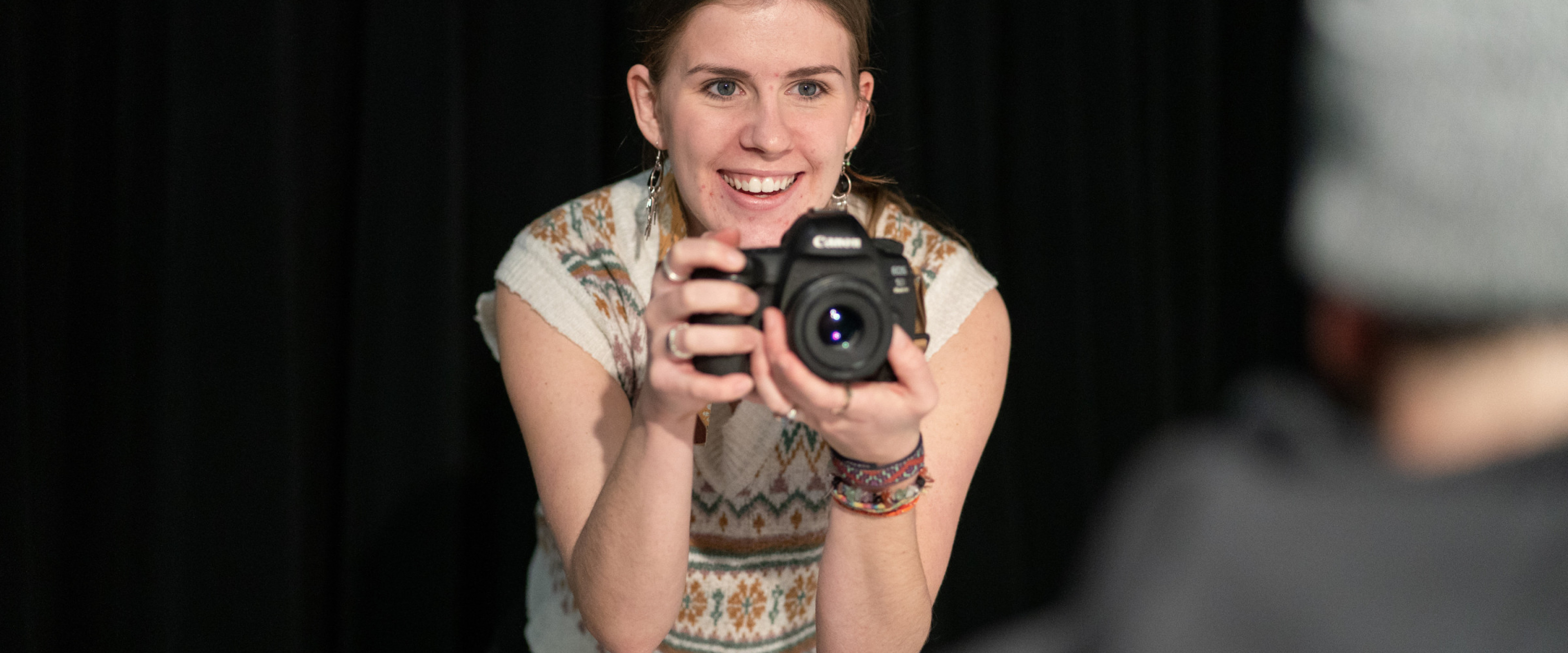 Alli Mitter, photography student, holding a camera in a lighting studio.