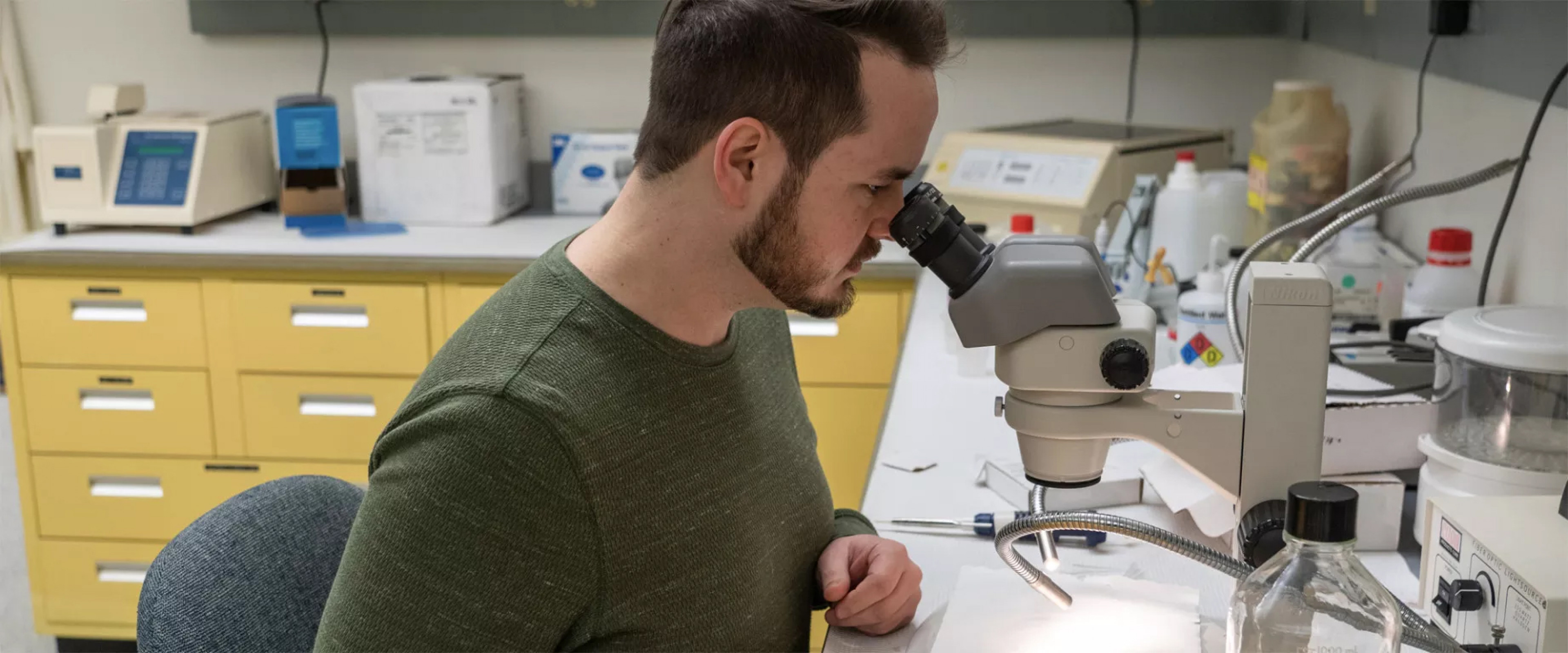 Student sitting in lab using a microscope