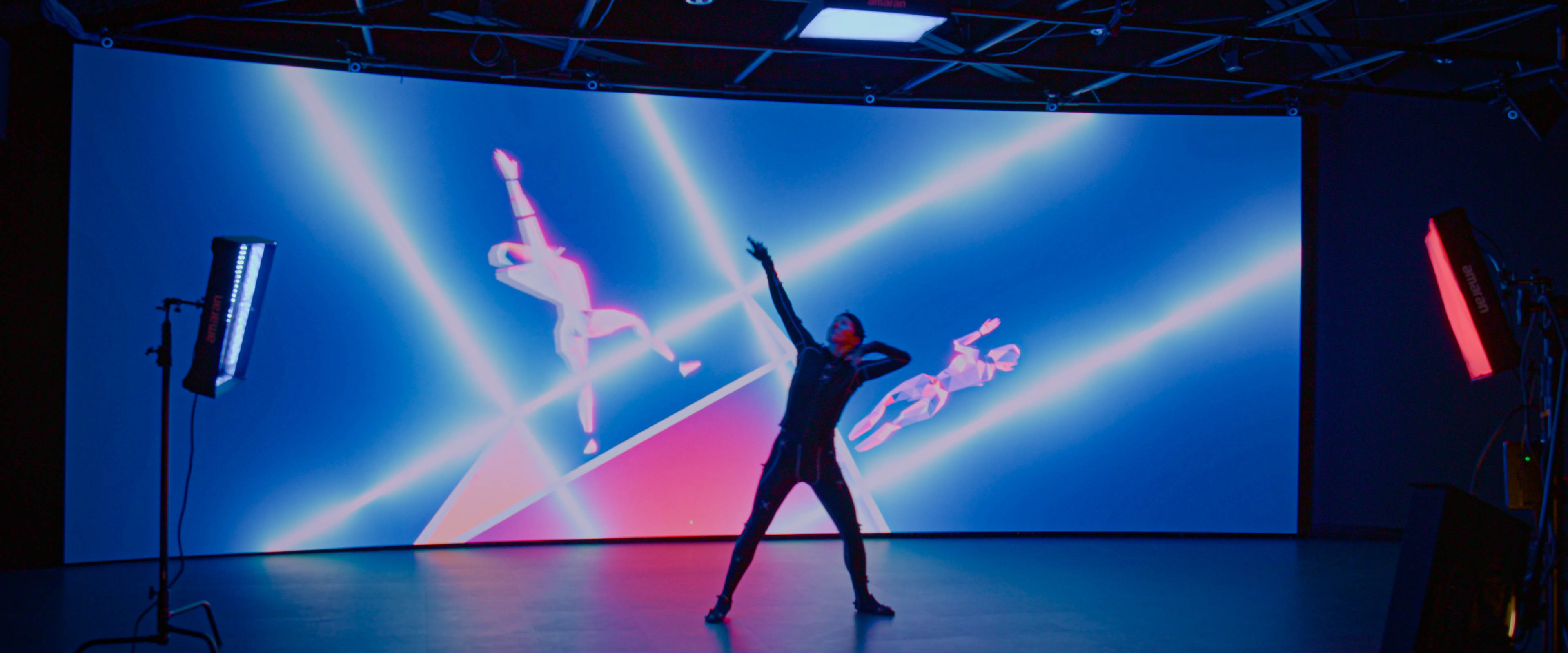 Dancer performing in motion capture with corresponding avatars on the LED wall.