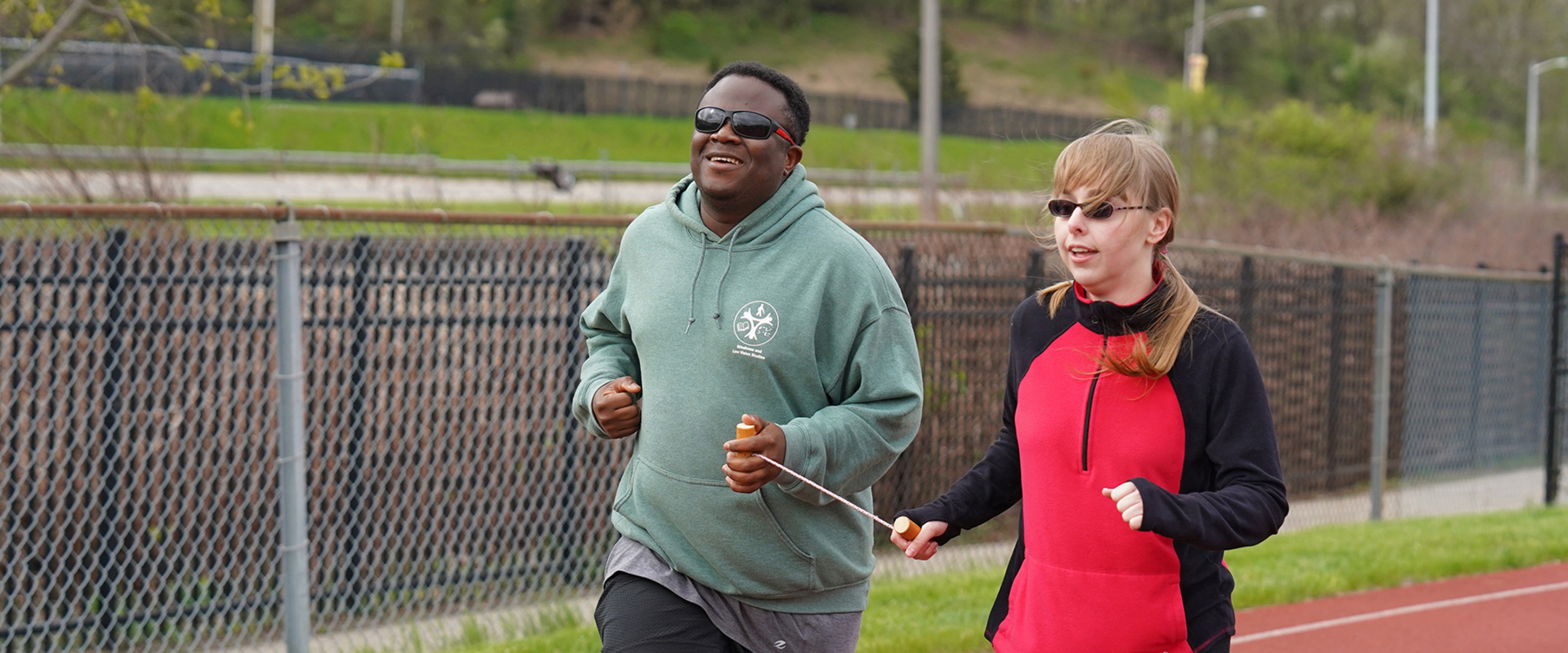 WMU student Osman Koroma exercising outdoors by running Western's track with an assistant