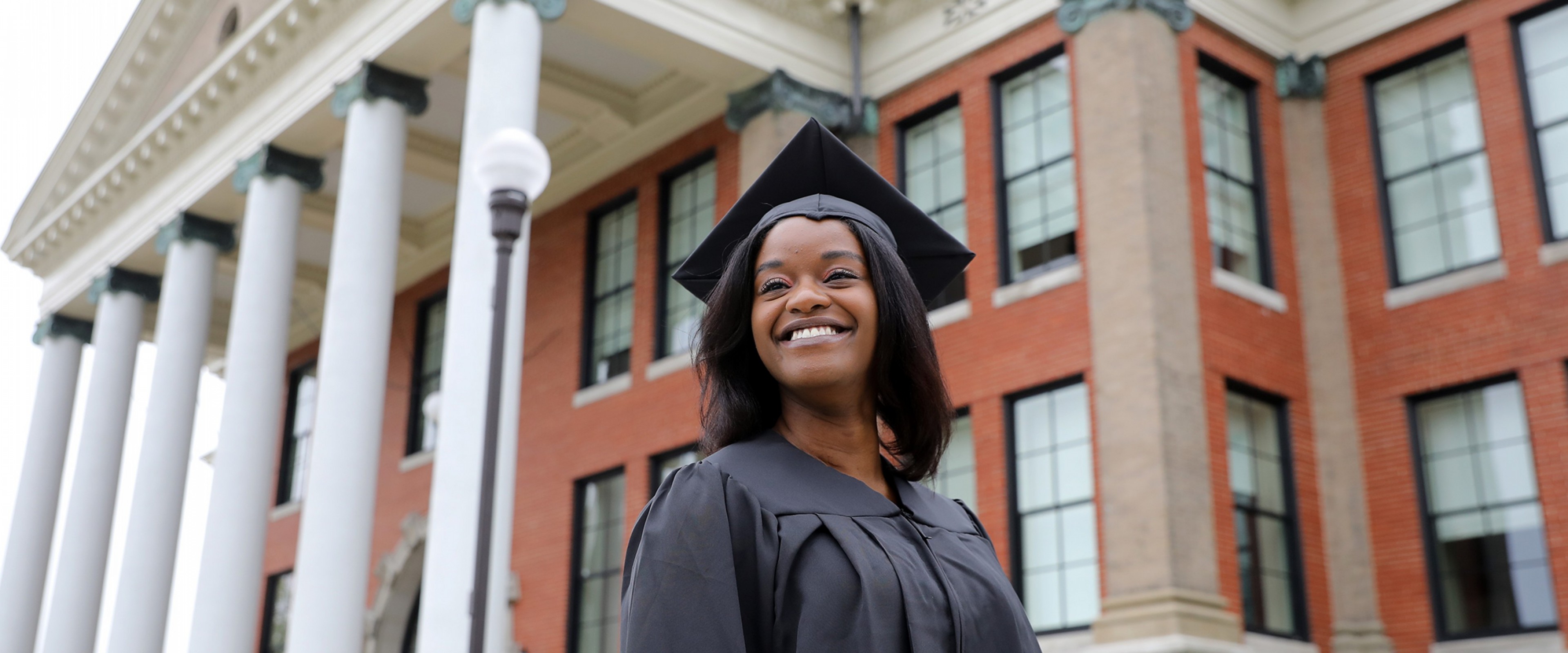 A smiling WMU graduate wearing her cap and gown
