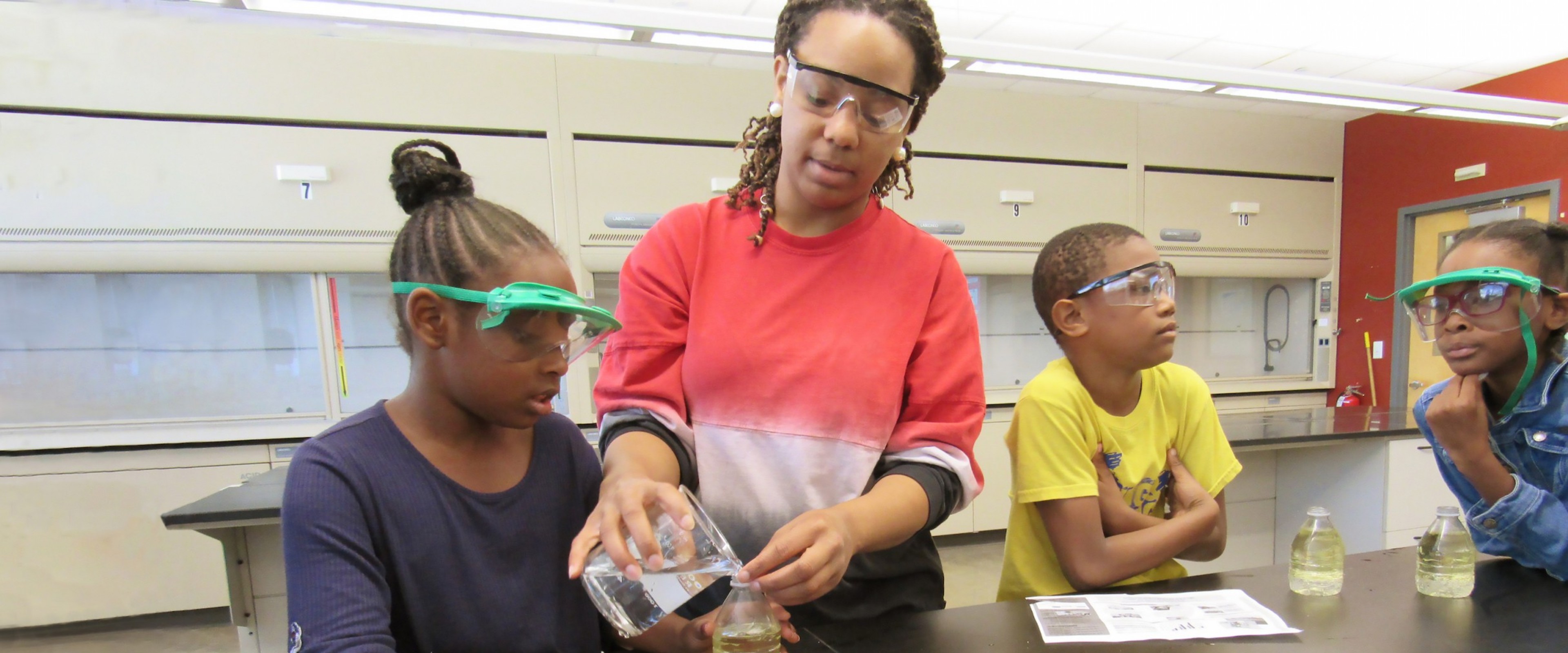 A graduate student does science experiments at a table with kids.