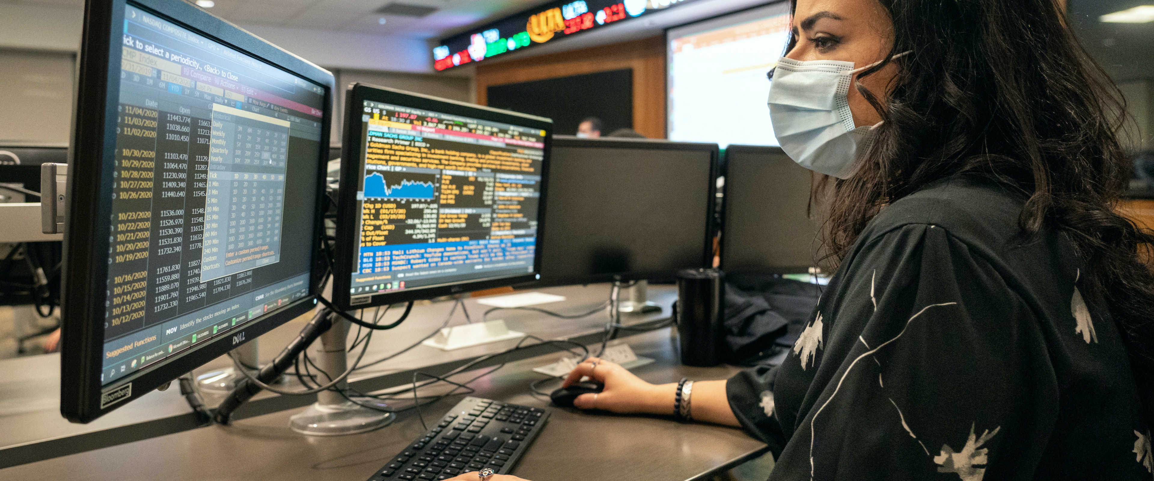 A masked student working on a computer in the Greenleaf Trust Trading Room