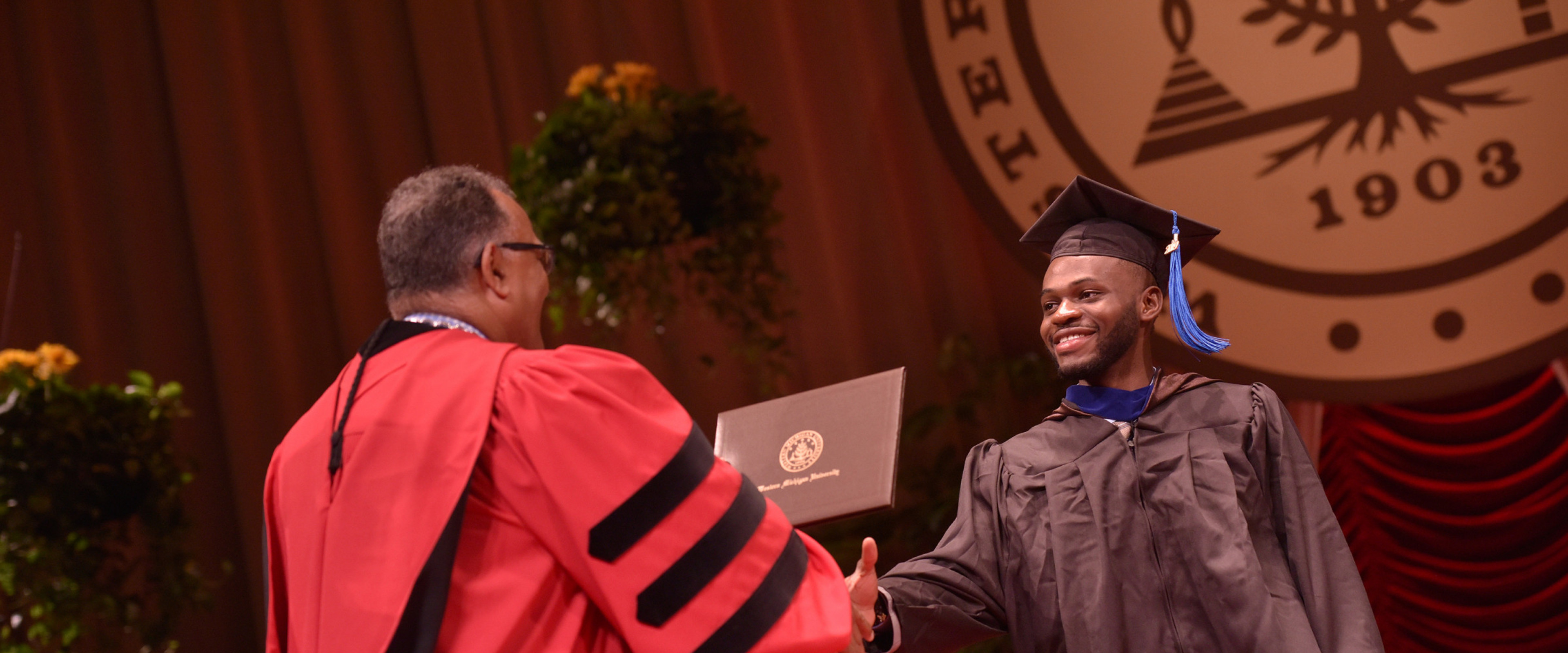 A graduate shaking hands with Dr. Montgomery while crossing the stage in Miller Auditorium