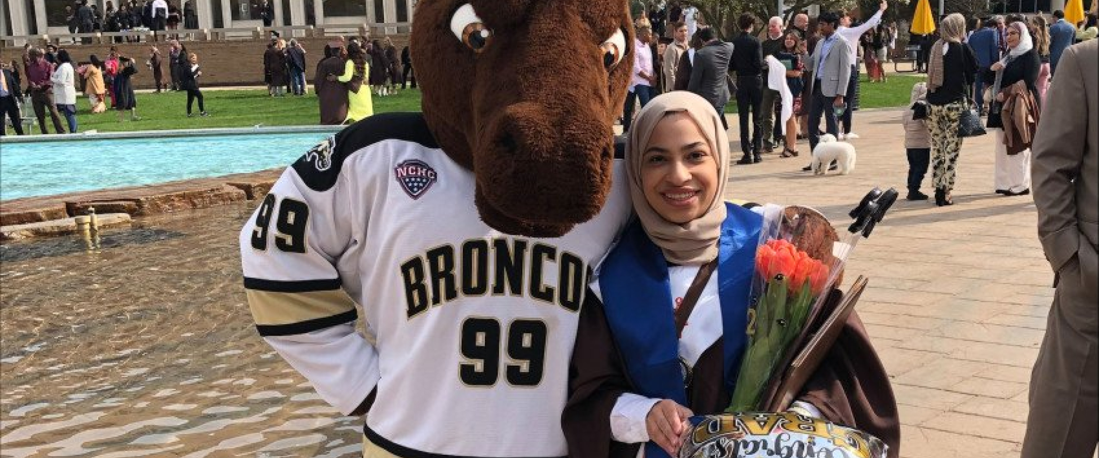 Student stands with Buster Bronco near WMU fountains