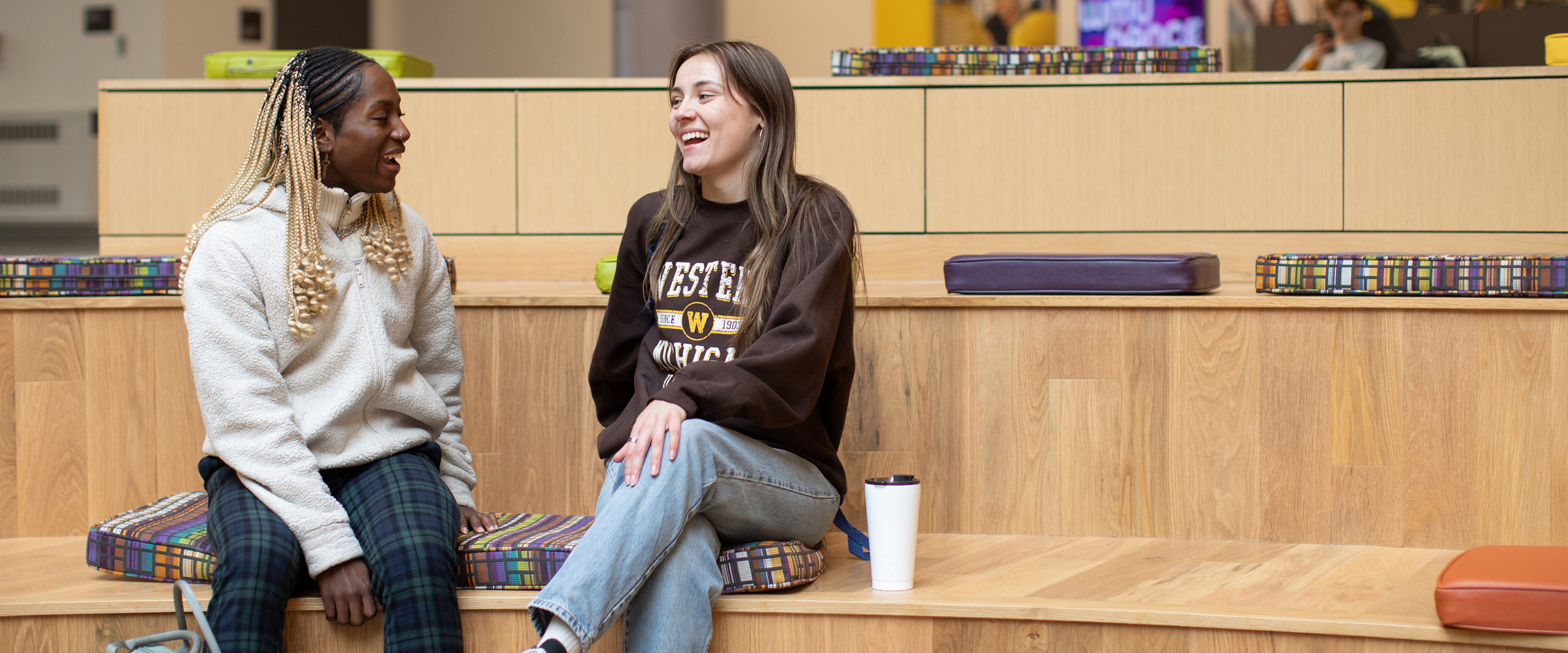 Two students laughing and sitting in student center