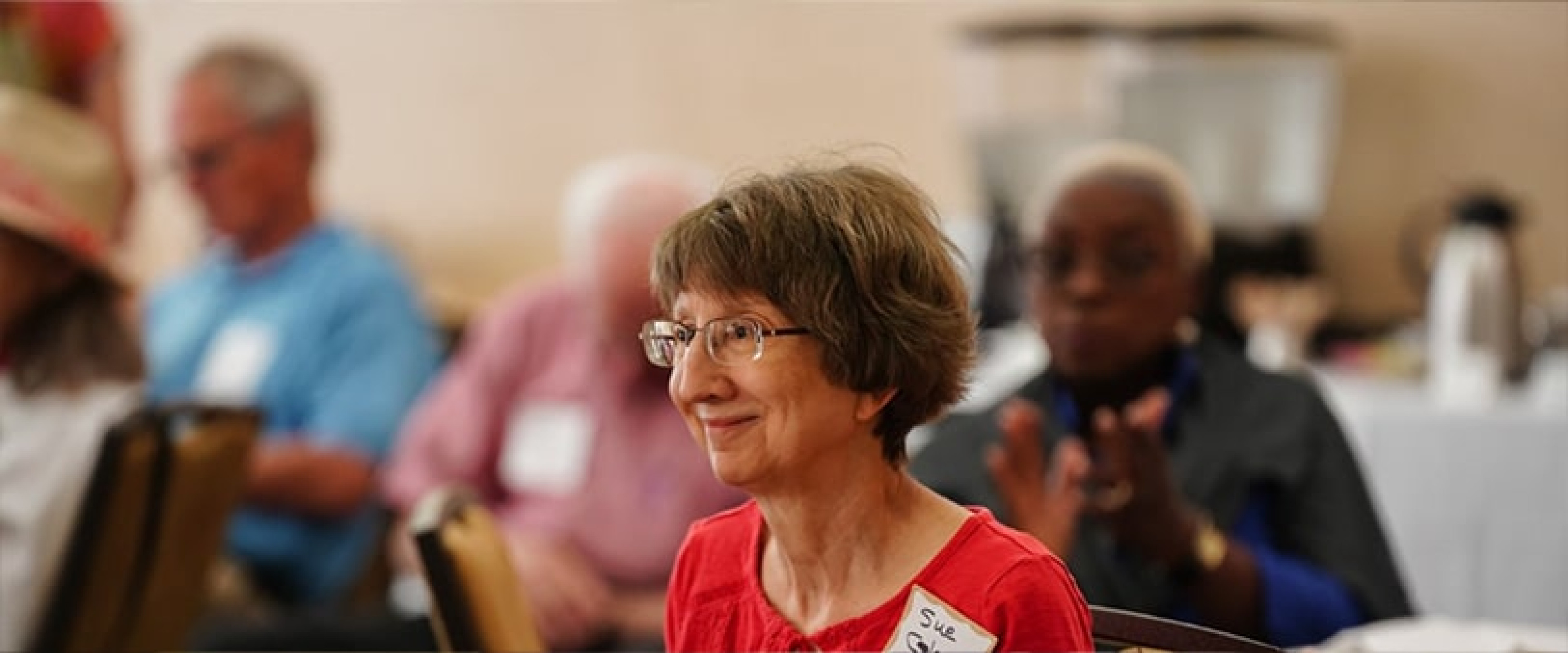 OLLI member in red shirt smiling during the reception.