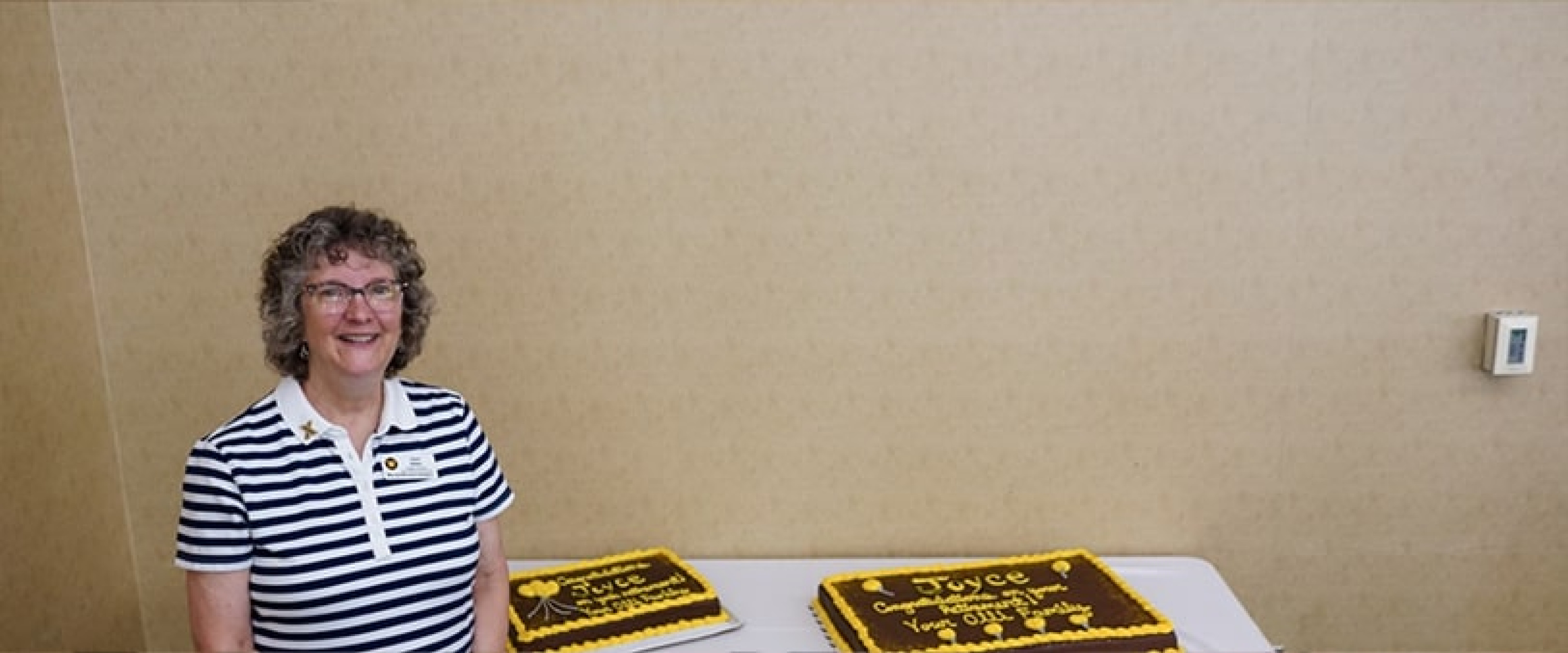 An OLLI staff member posing next to the reception cakes.