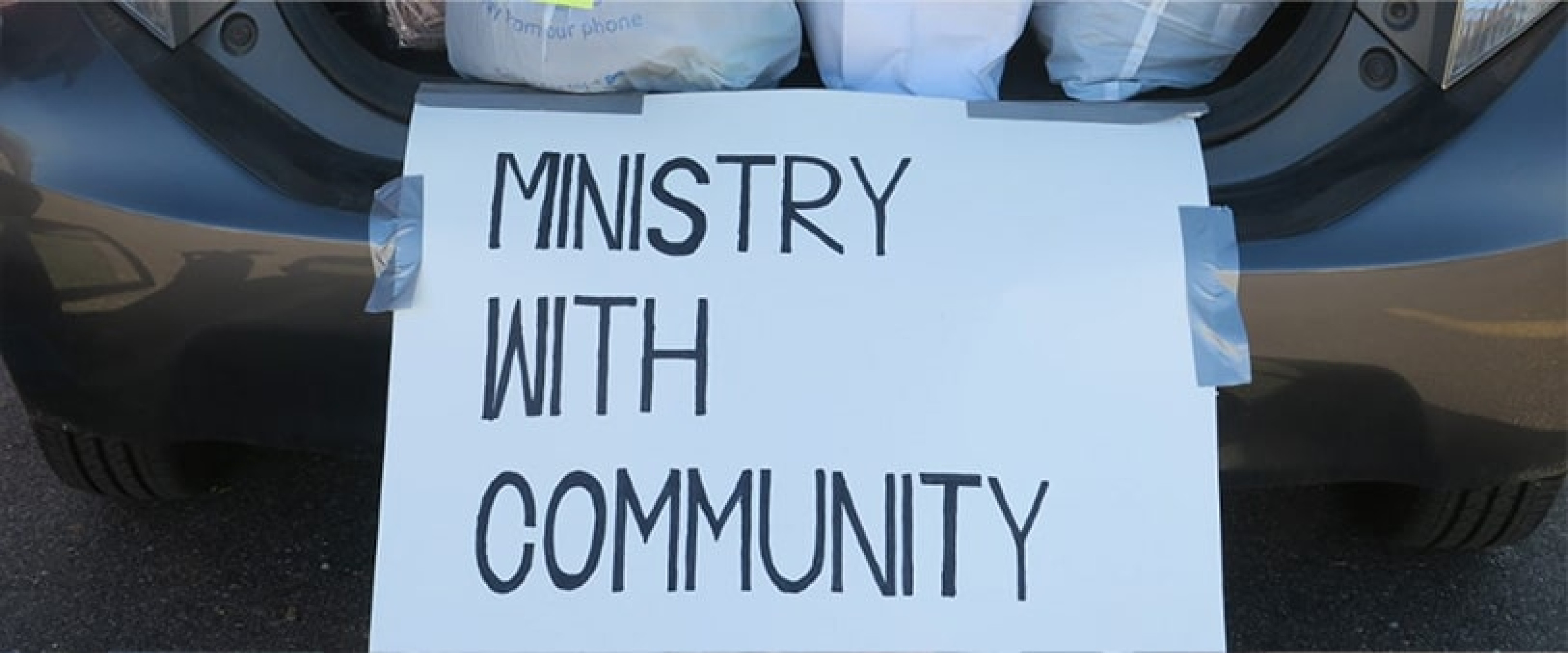 Ministry with Community sign taped to the back of a vehicle 