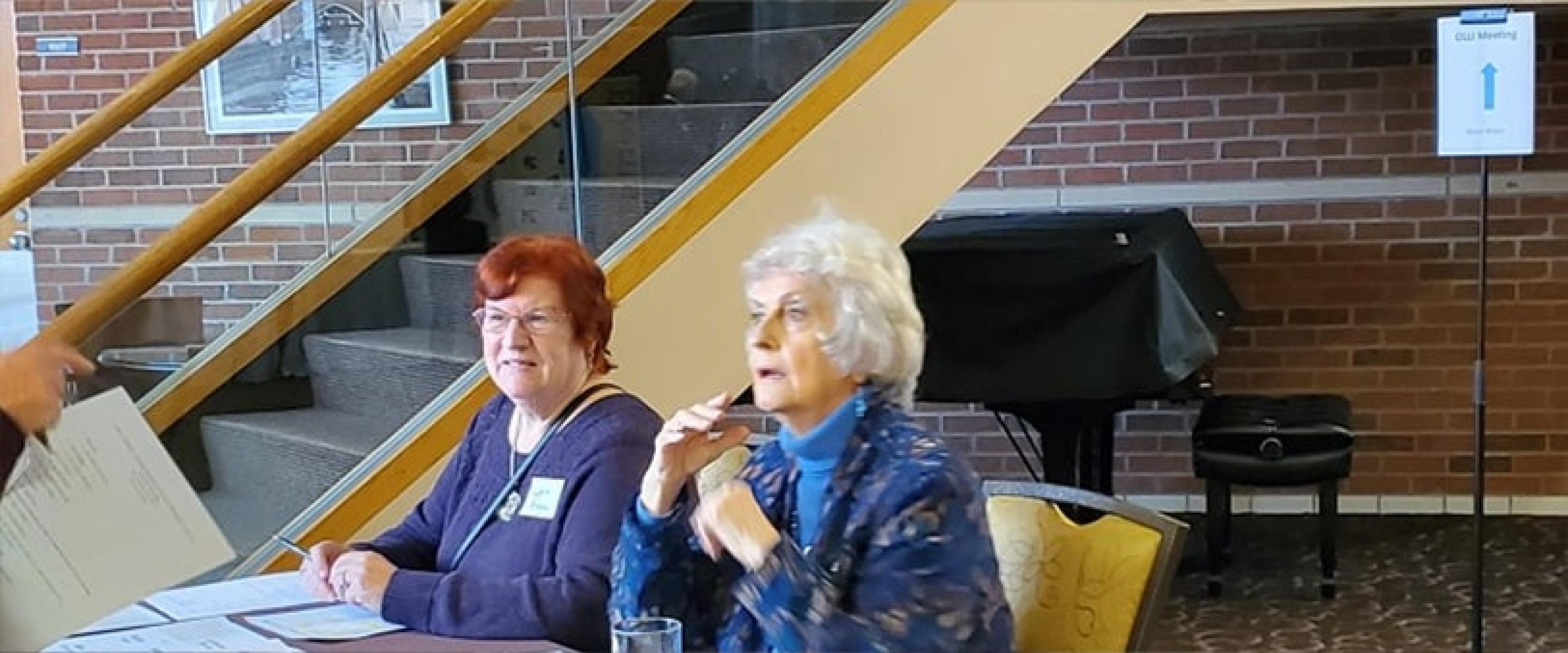 Two ladies at the check in table greeting arriving OLLI members.