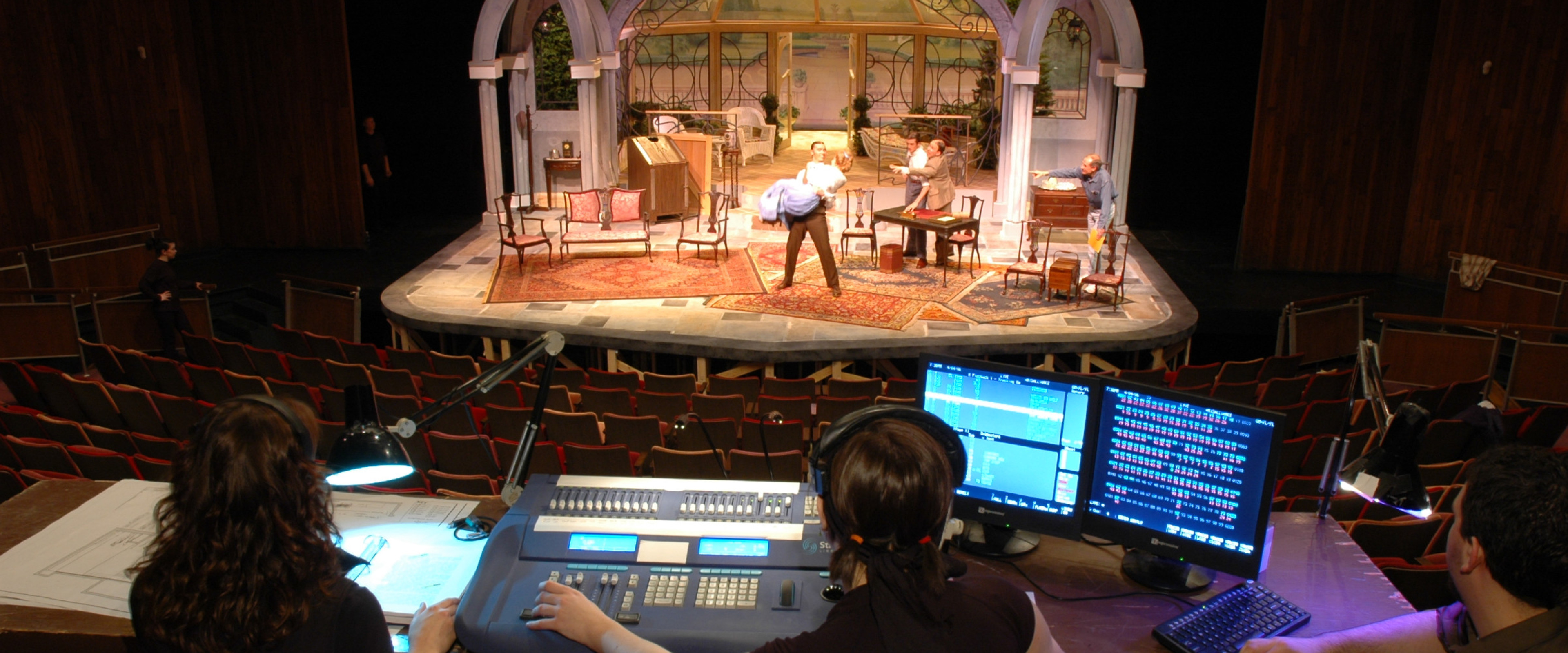 Theatre seen from behind work table with performance on stage.