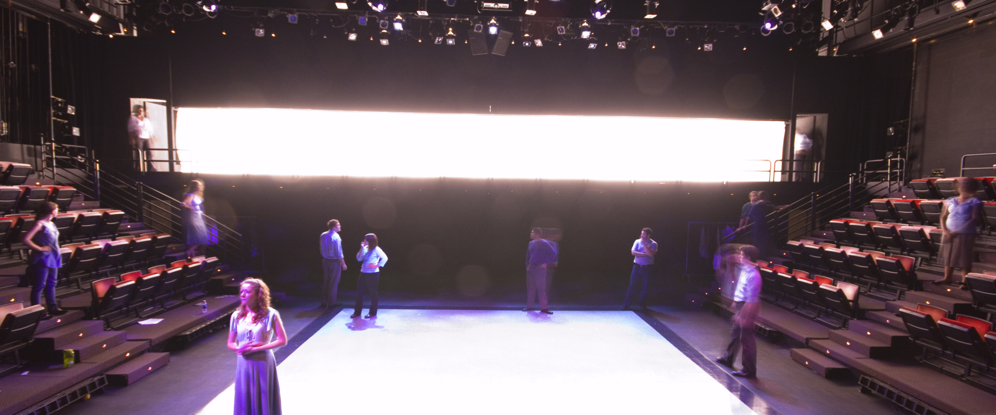 Students working in a lit black box theatre.