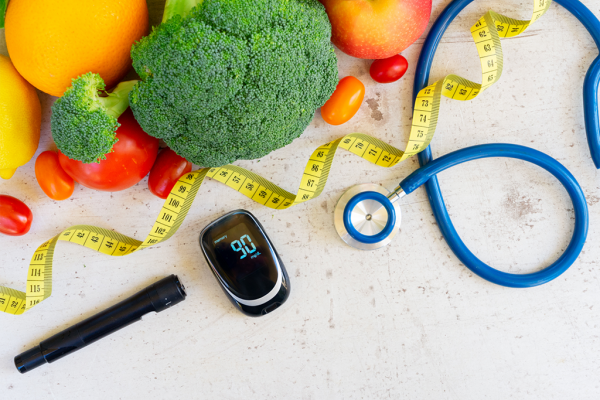 vegetables displayed with a stethoscope, tape measure and diabetes calculator