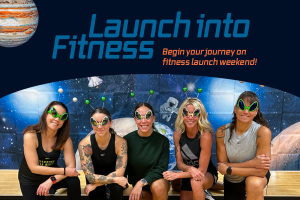 Group fitness trainers in front of a space themed backdrop with planets and blue sapce