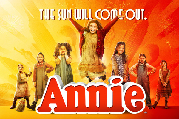 Annie jumping in the middle of six girls with the Annie Logo underhneath