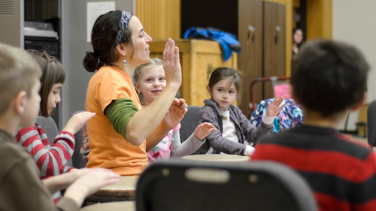 female drum instructor teaching a group of small children