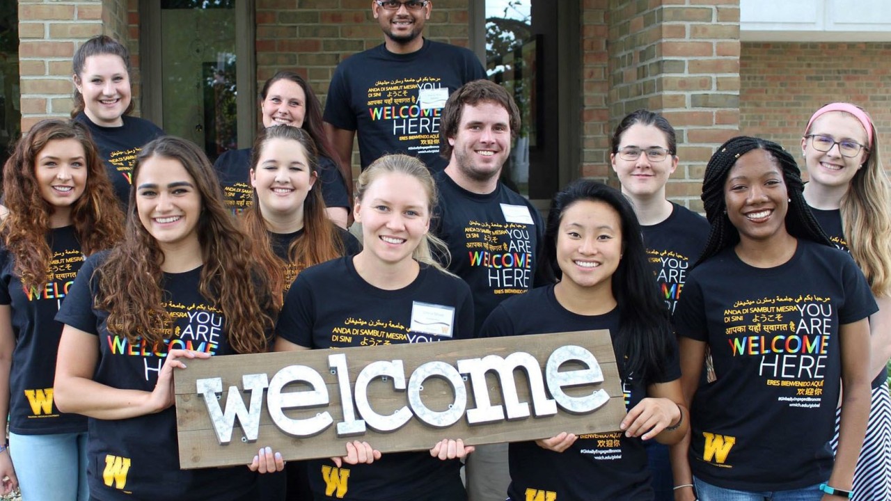 10 DSS student peer mentors smiling and holding a sign that says Welcome