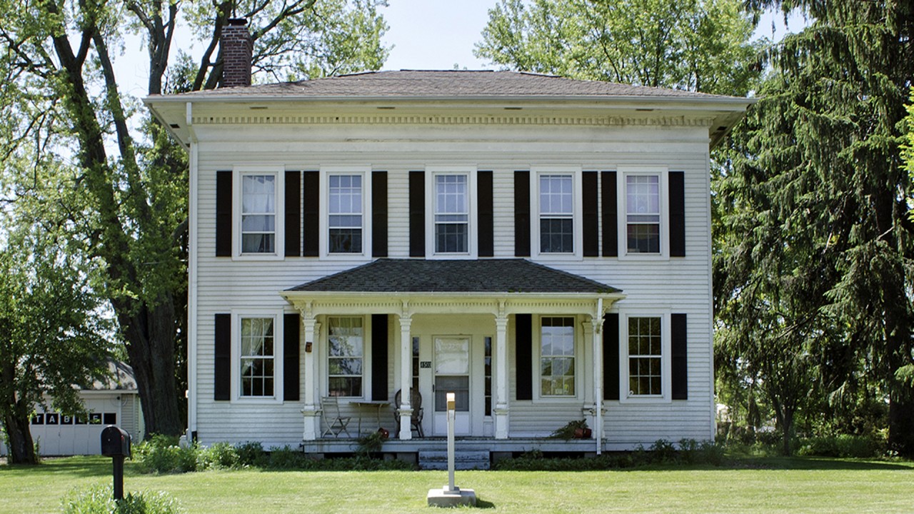 a white, plantation style home on WMU's campus against a backdrop of trees and vegetation