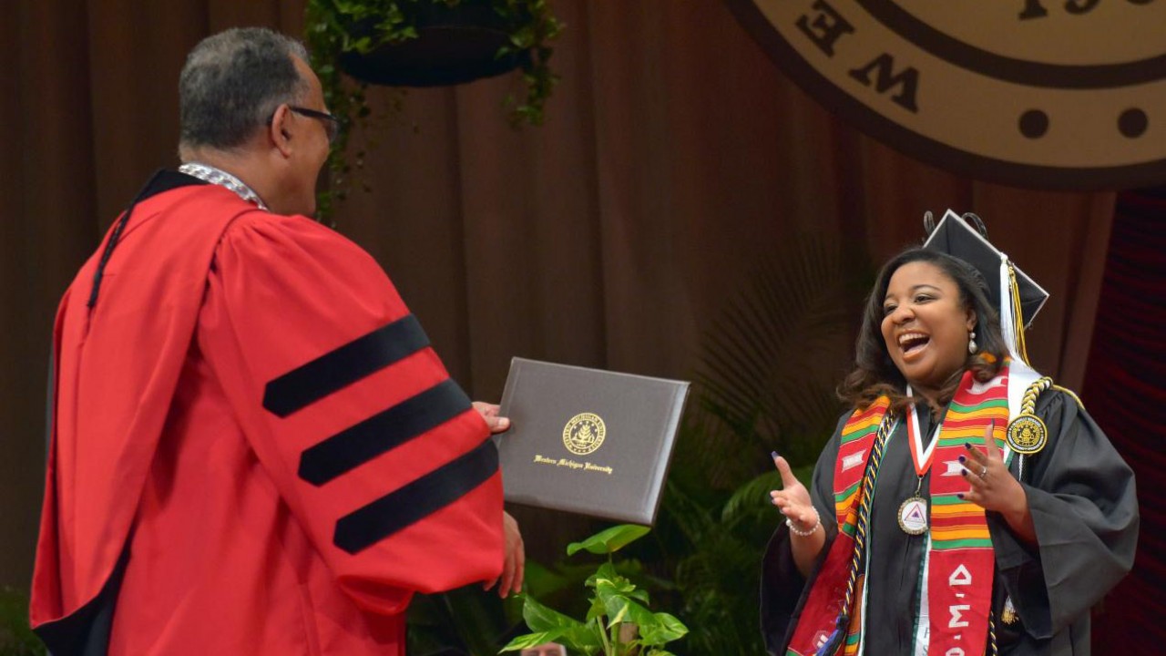A smiling student preparing to shake Dr. Montgomery's hand and receive a diploma during commencement