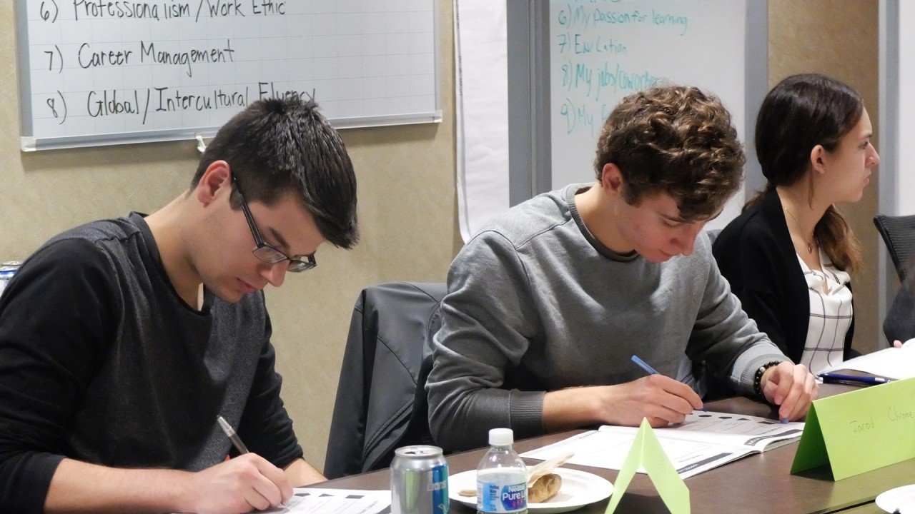 Three students working in the conference room of the Zhang Career Center during a workshop.