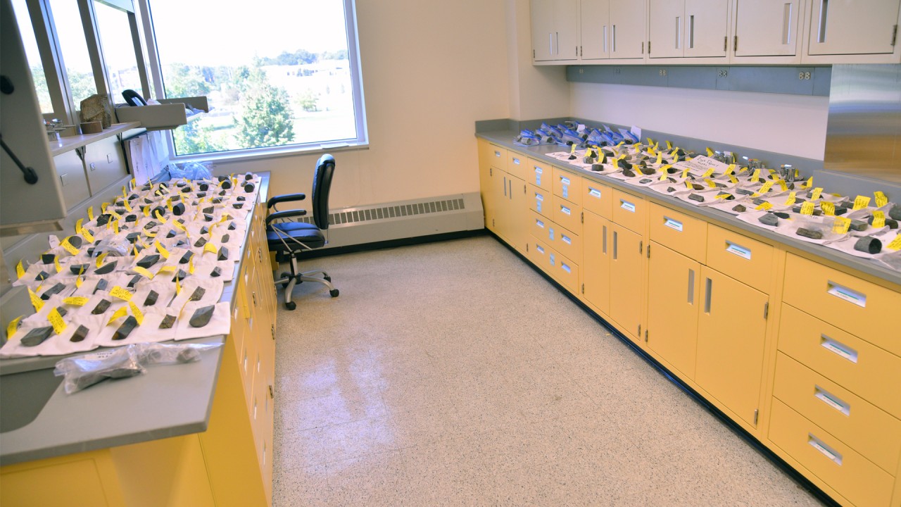 Two long countertops in laboratory with  samples of rocks displayed on both