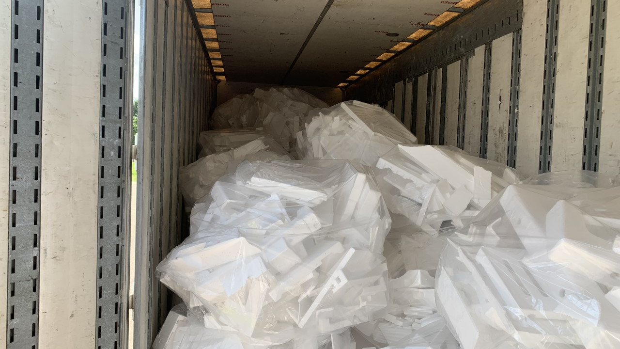 Stacks of Styrofoam bagged and sitting inside the back of a large box truck.