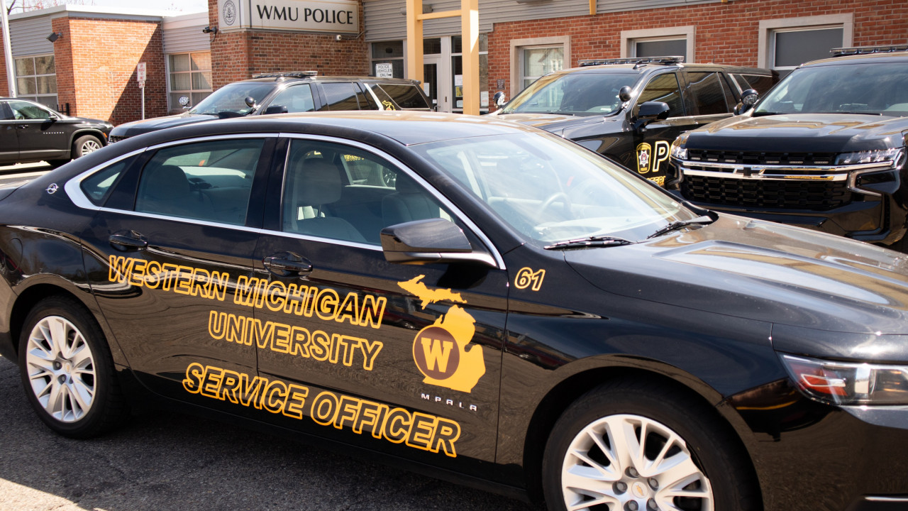 A WMU service officer vehicle is seen in front of the department of public safety building. The vehicle is black with logos that say Western Michigan University Service Officer.