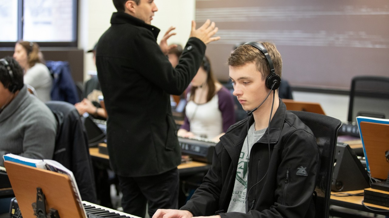 student with headphones working on a keyboard in class