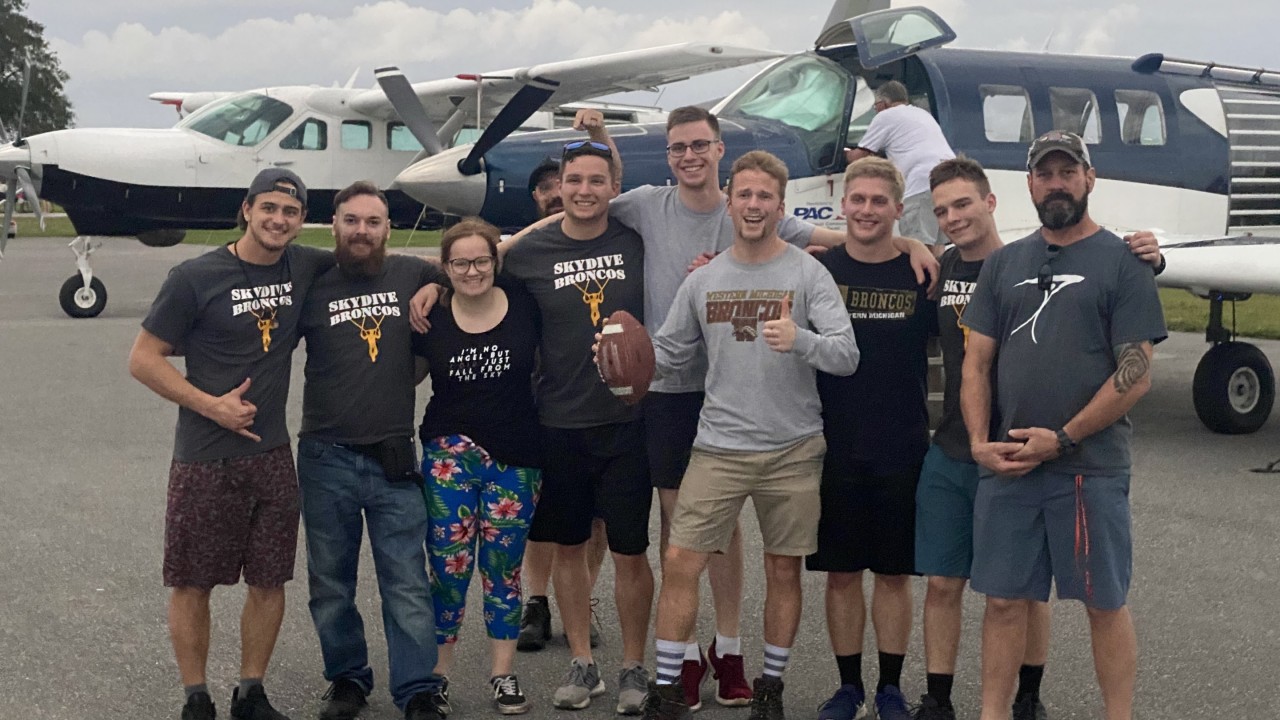 The Sky Dive Broncos club standing in front of a plane