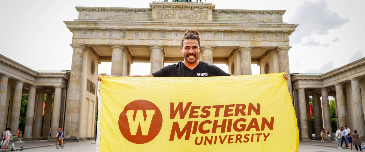 A marketing student in Germany, holding a WMU flag.